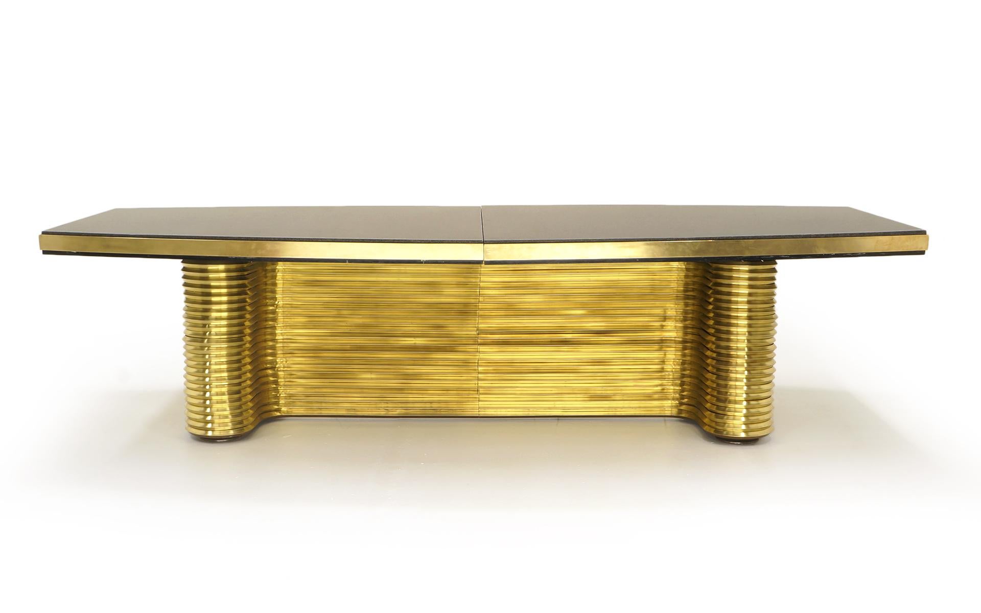 Stunning brass and granite table designed by Ed Moore, 1980s. The base is solid brass and steel. The two part top is charcoal granite framed in the solid brass skirt. This table is almost ten feet long. This is a seriously impressive and beautiful