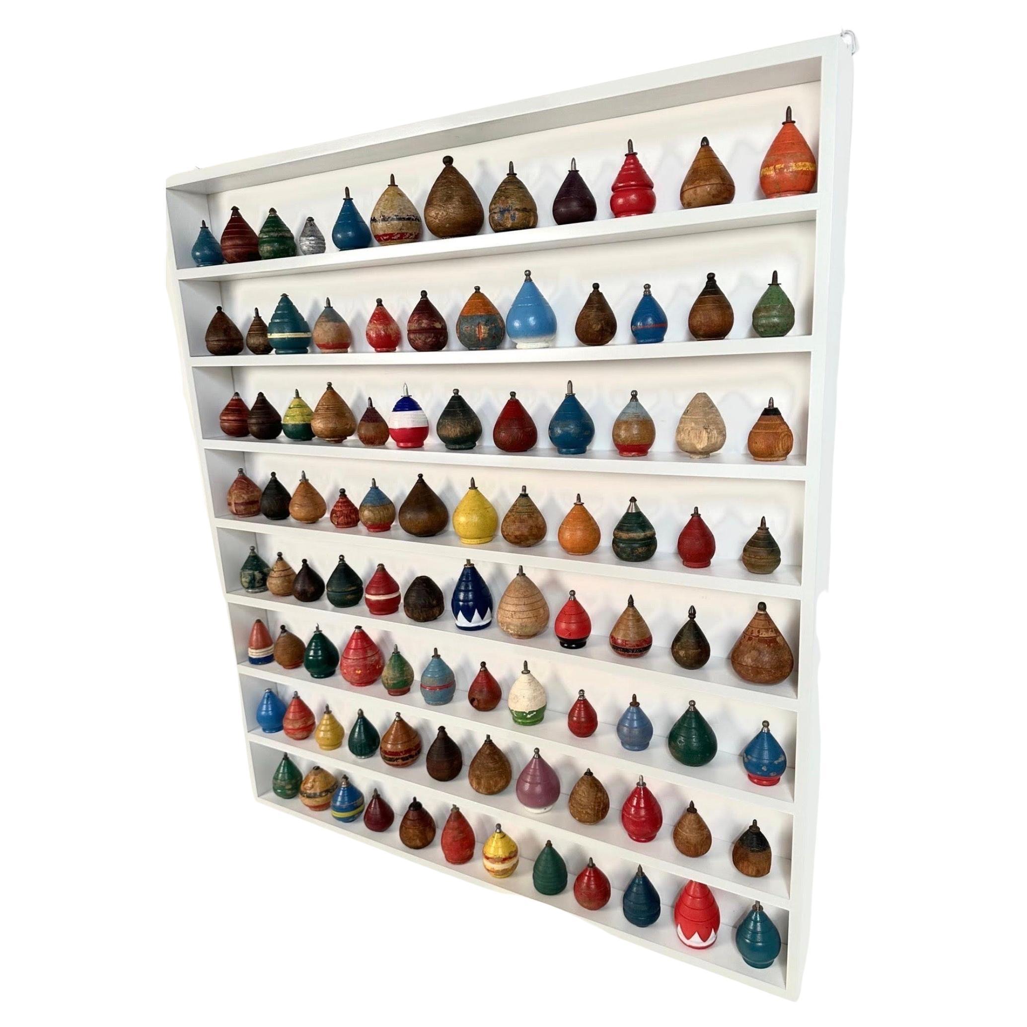 A great graphic collection of 98 antique toy wooden spinning tops of various shapes and colors dating from 1880 to 1960.
This collection is displayed in a high quality custom made white painted maple display. The tops can be arranged in any