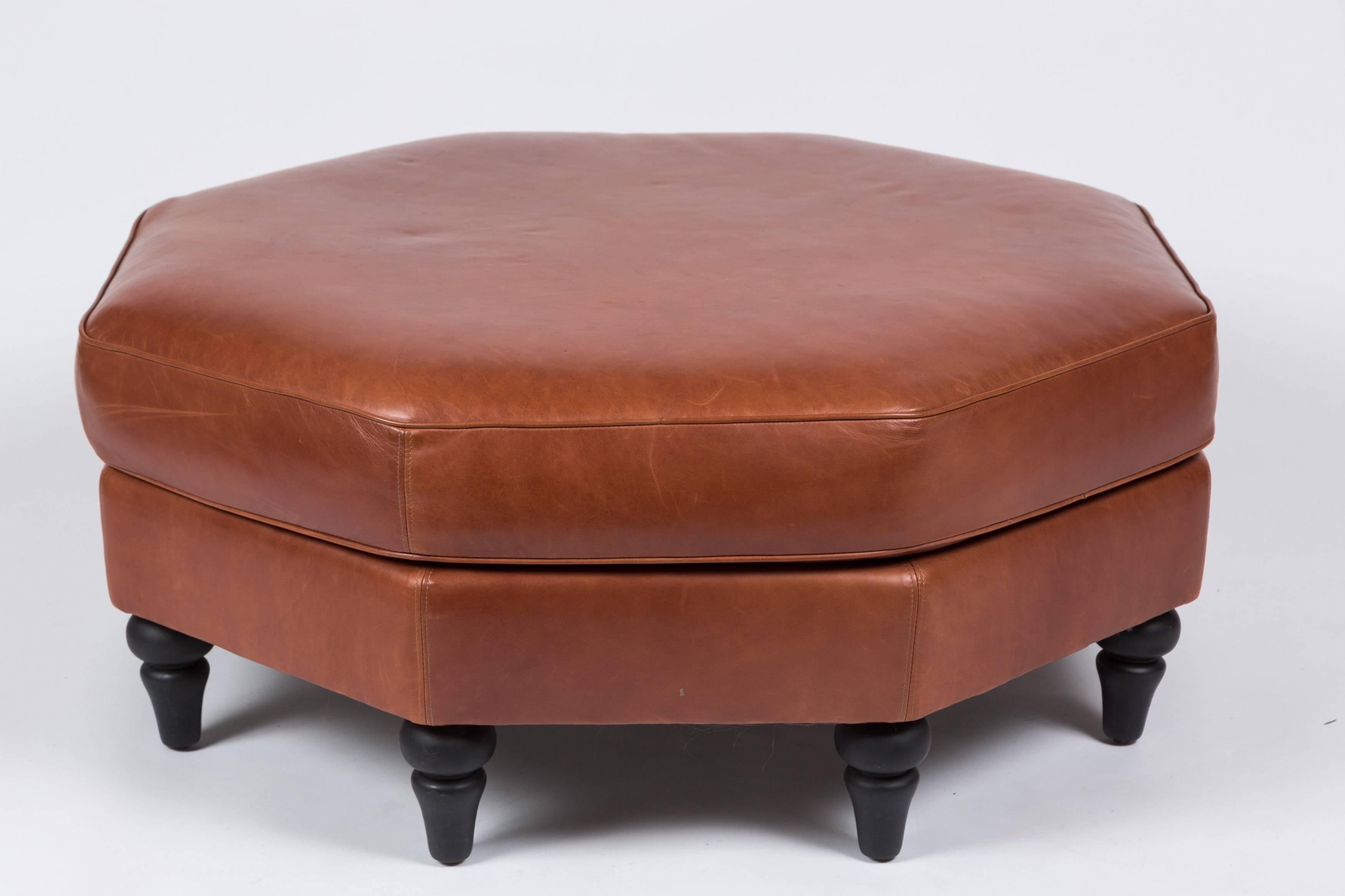 Large octagonal leather ottoman with turned wood legs upholstered in Moore & Giles Diablo in Cognac. 