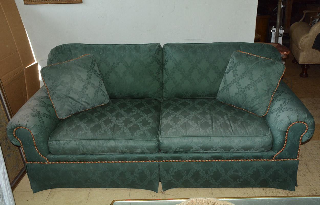 Two-seat upholstered sofa featuring classic English style rolled arm design. Upholstered and completely skirted on all sides this sofa was made by Kravet one of the finest furniture makers in the country. Upholstery is faded on the right arm