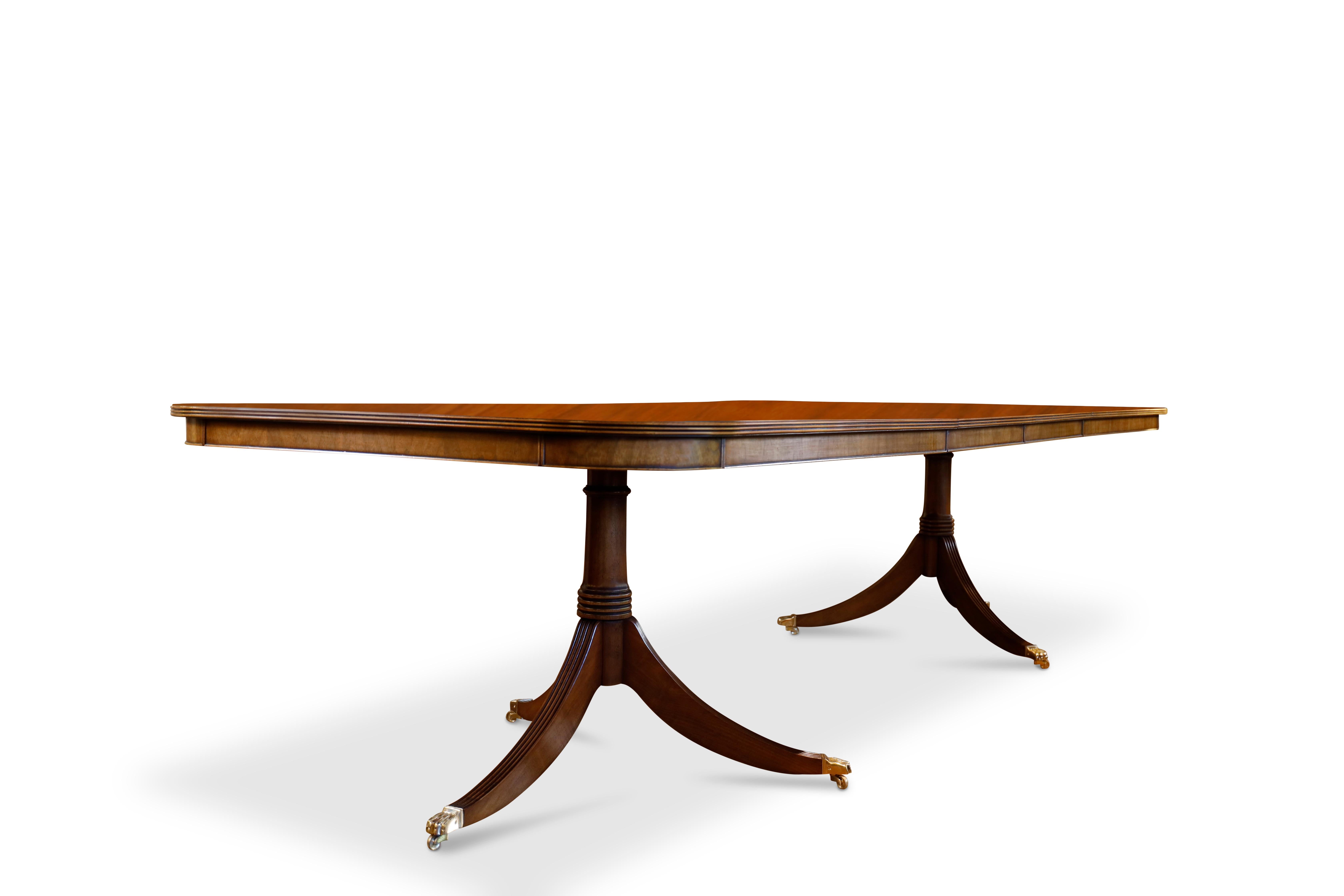Regency style two-pedestal, two-leaf walnut dining table with burl walnut crossbanding, beaded edge, and walnut apron.  Cannon turned single column pedestals with reeded legs ending in brass 