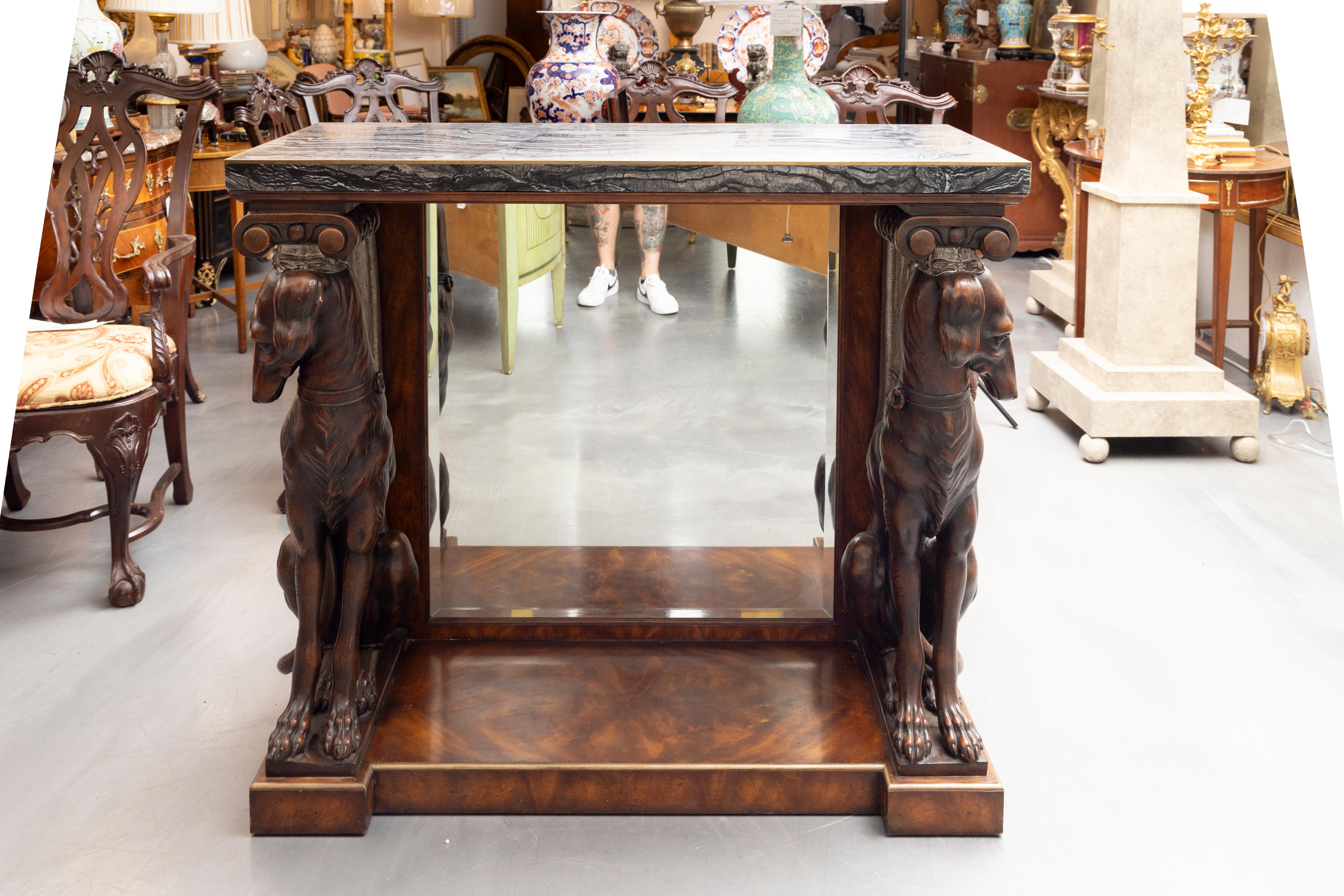 This is a unique custom designed console with a stone top edged in brass over a mirrored back-panel flanked by two prominent fabricated Whippets situated on a mahogany wood plinth with brass molding.