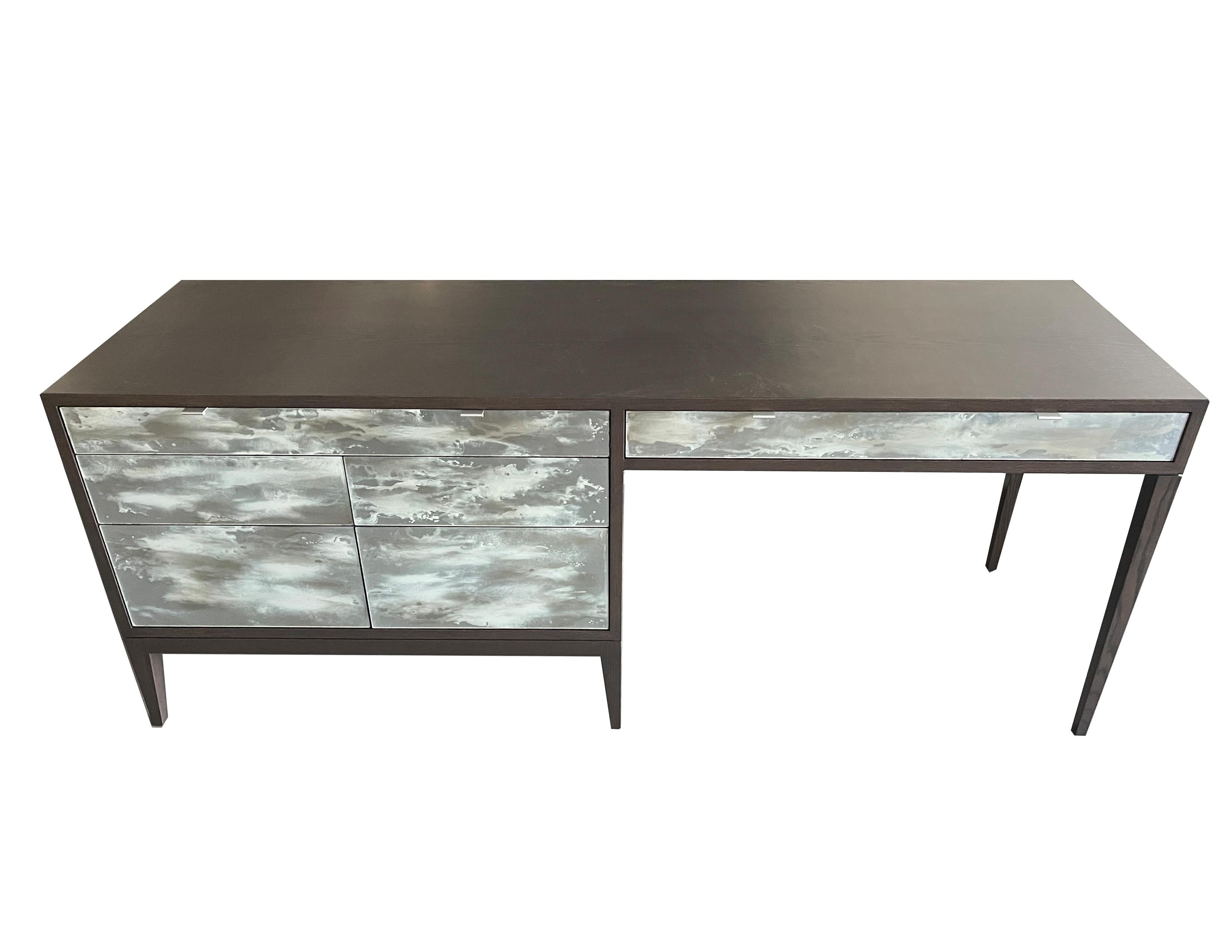 The Custom Galaxy desk by Ercole Home is six drawer dresser with a connected desk workspace that has one pencil drawer. The desk is made of Oak and has a Earl Gray Paint finish. The drawers of this piece are covered in our one of a kind hand painted