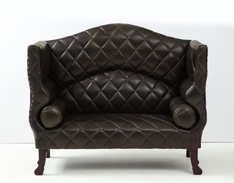 An original custom made soft mottled black leather tufted with brass tacks and mahogany wood legs by famed bespoke British furniture maker, George Smith. Original label. Excellent condition. The black color has hues of blackbrown, and hint of olive.