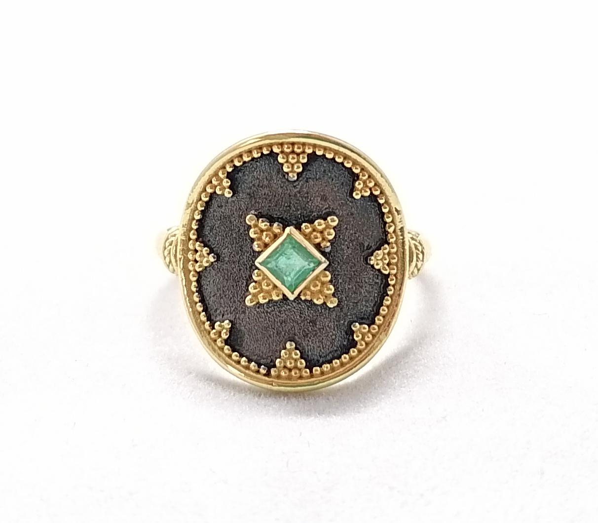 S.Georgios designer two-tone Stunning Ring is handmade in solid 18 Karat Yellow Gold and is microscopically decorated with Byzantine-style granulation work. This beautiful ring features an elegant center Princess cut natural Emerald total weight of
