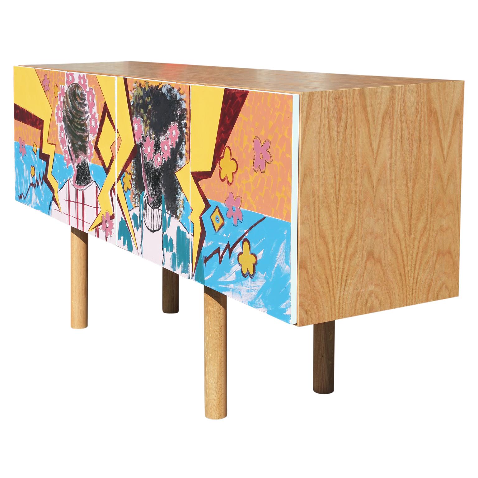 Custom hand-painted credenza made in collaboration with Houston, TX artist, Alexis Pye. This credenza features two abstracted vibrant figures of a man and a woman with pink, blue, and yellow floral and geometric shapes. Its smoothly turned legs