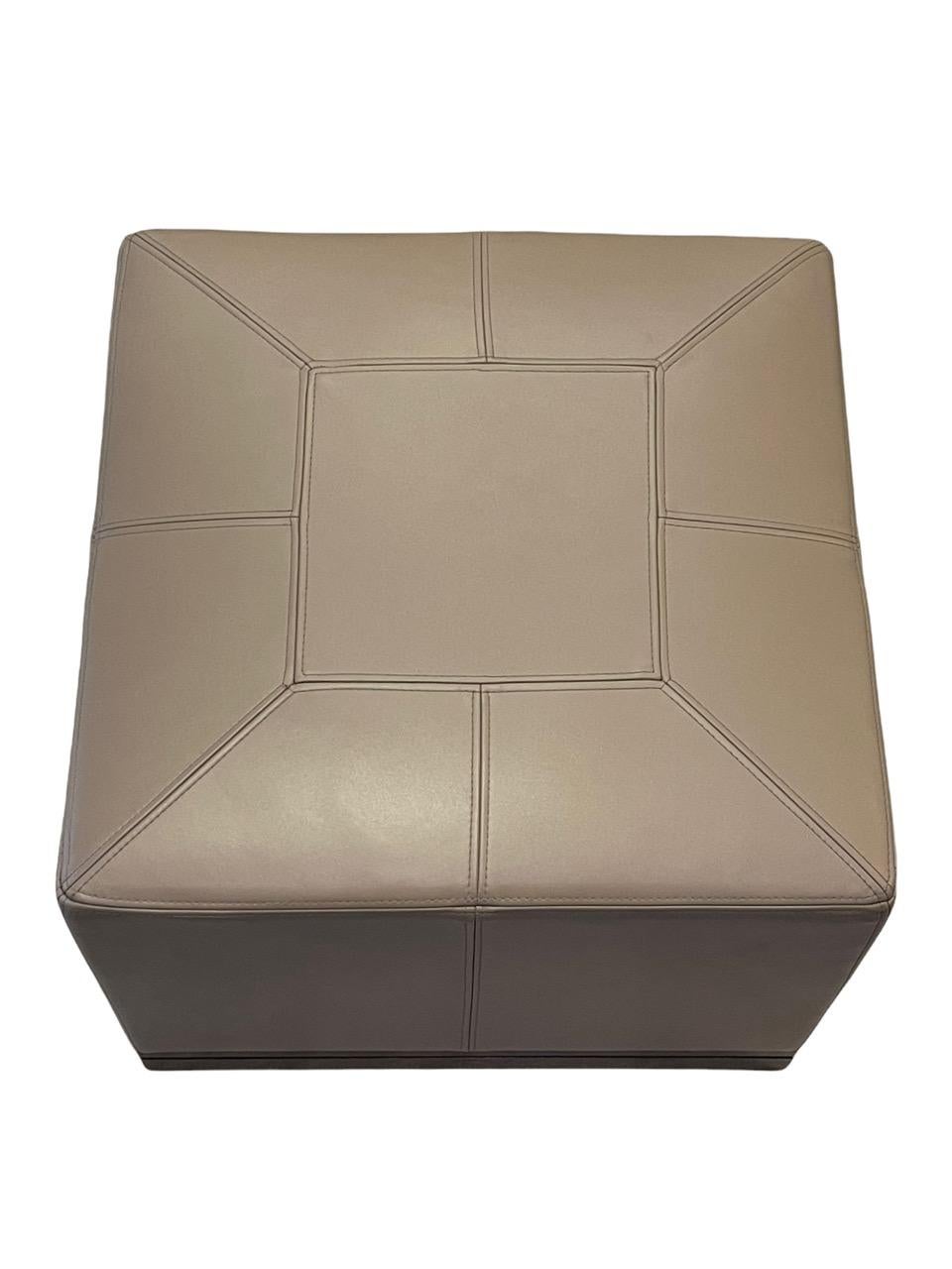 Custom Holly Hunt Archipelago ottoman in taupe color. It is designed with linear stitching pattern and walnut base. The brand is very unique and offers a curated experience featuring their designs as well as represented collections from designers,