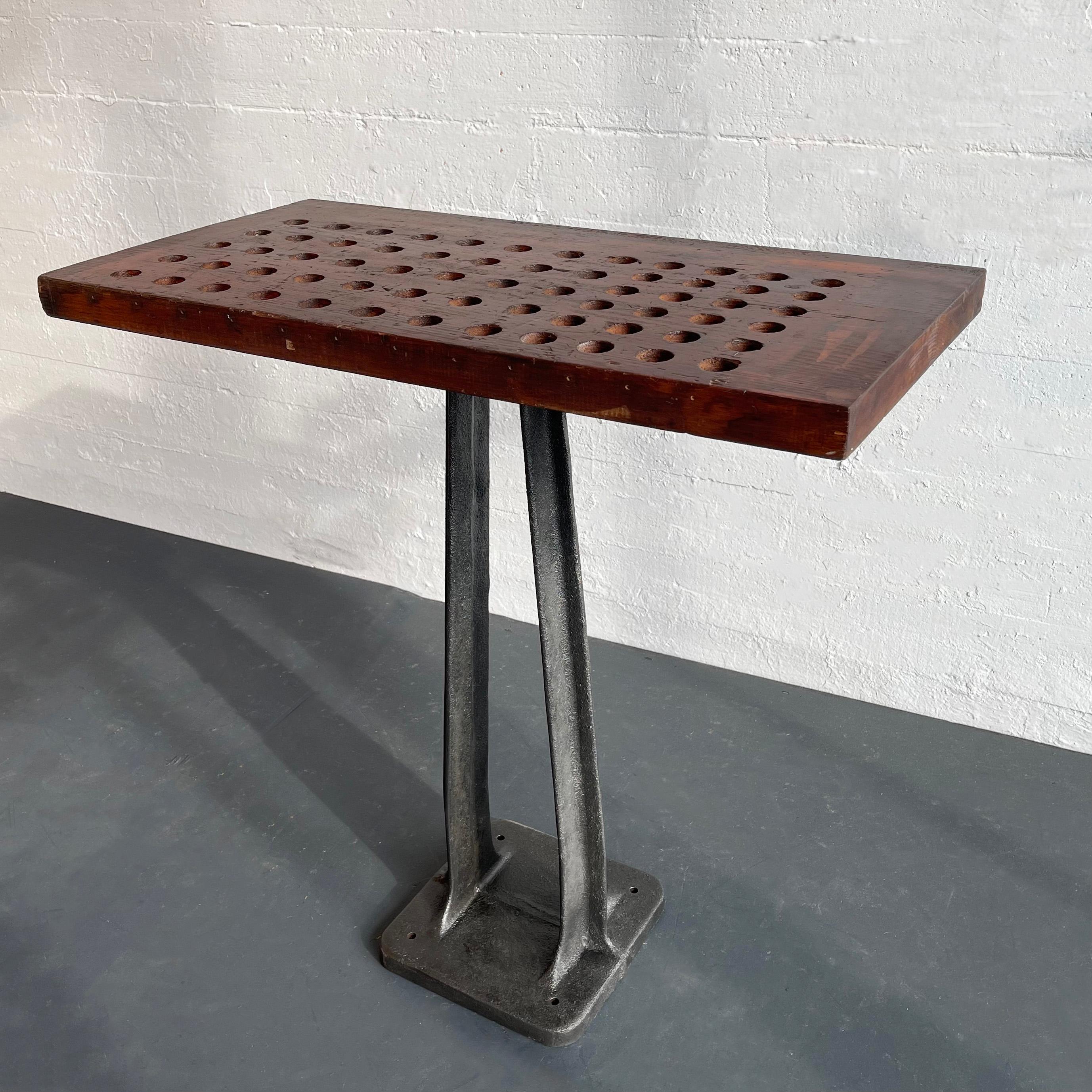 This custom-built industrial console table features a newly brushed, cast iron machine base with a rounded corner floor plate with pre-drilled holes for floor mounting if desired. The base is topped with a reclaimed perforated stained pine tool