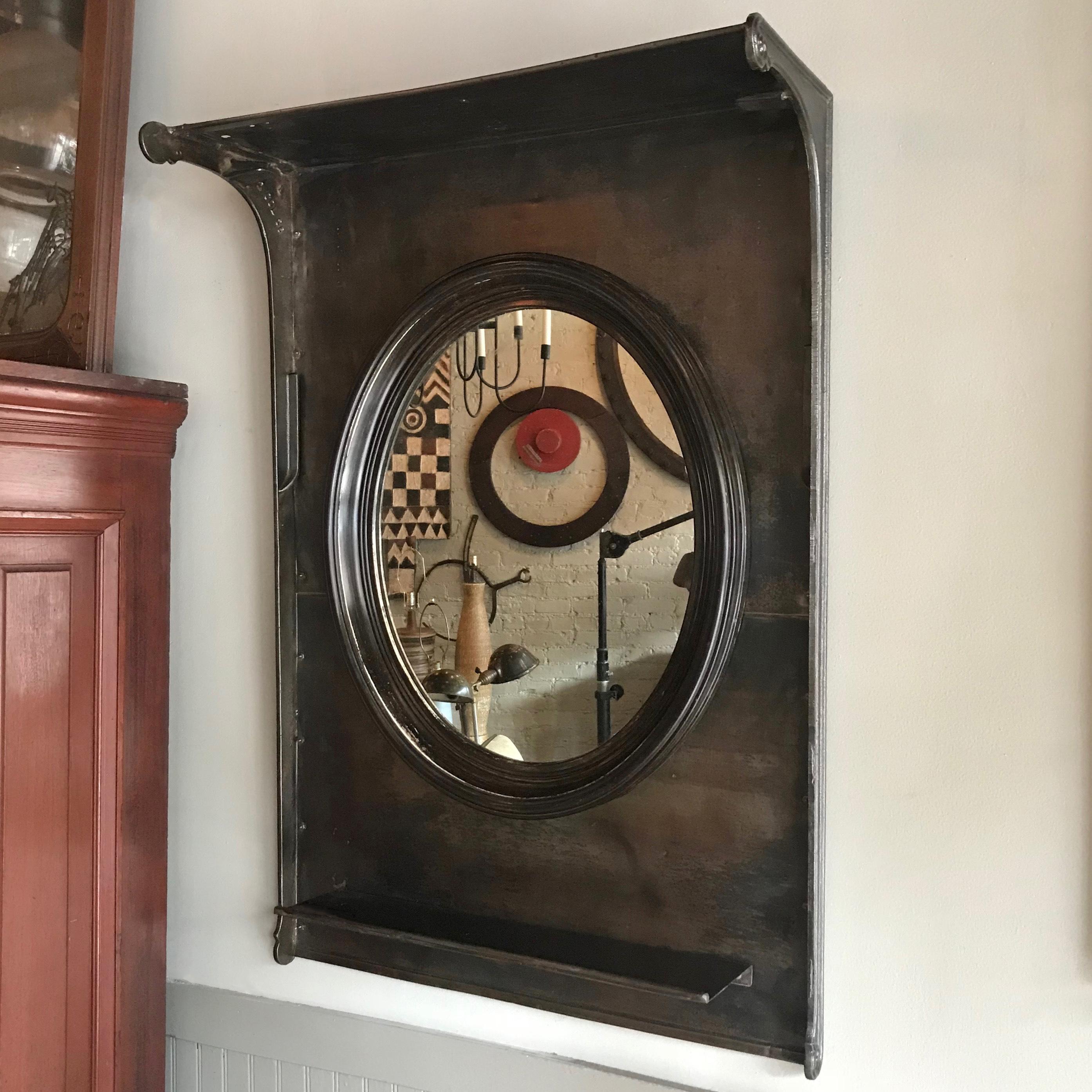 Custom, industrial, entryway or foyer piece comprised of vintage components features an oval wood frame mirror against a gunmetal steel surround with shelf. The mirror measures 23.5 inches x 19.5 inches and the shelf meausures 10 inches wide x 5