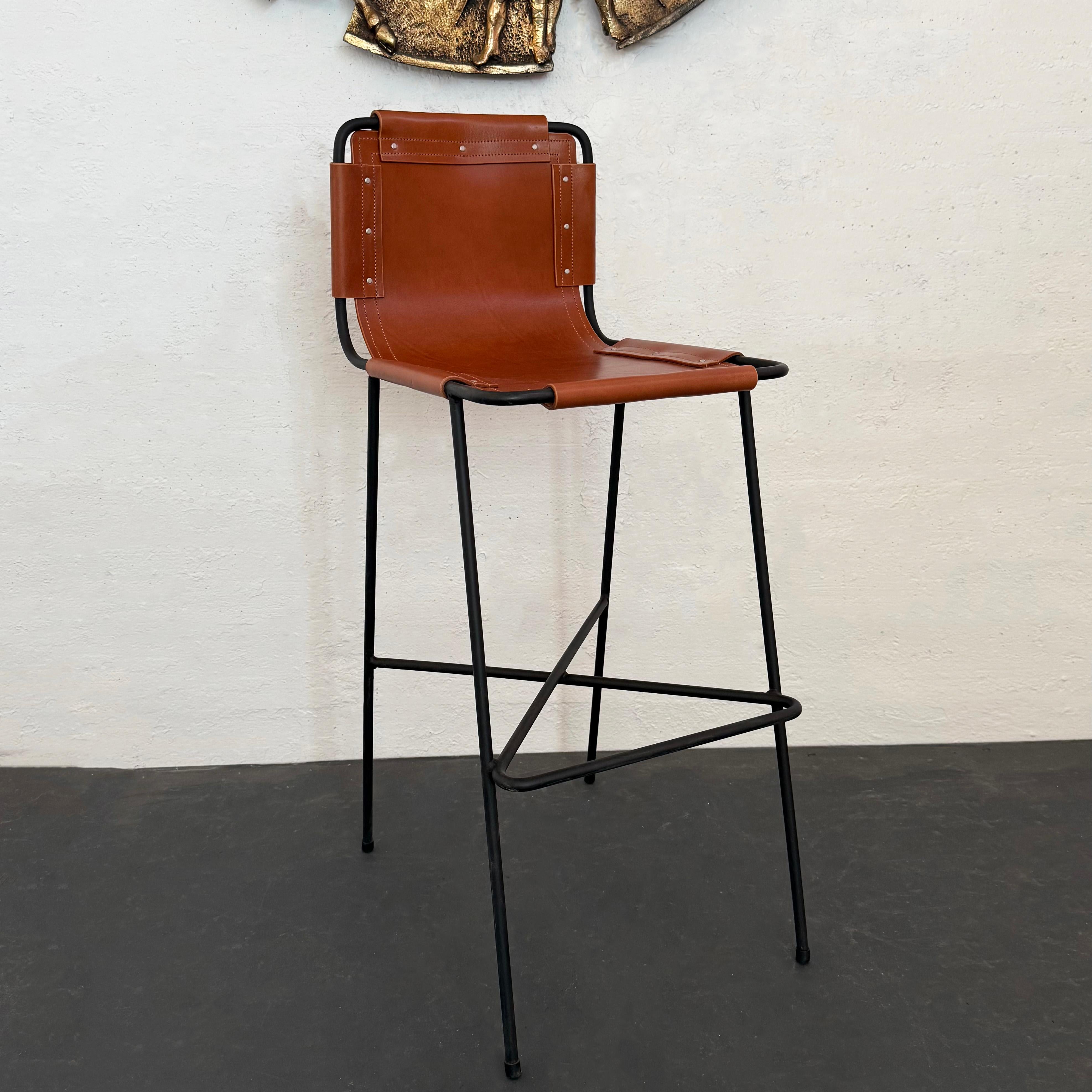 Architectural inspiration and mixed materials give our limited edition, cFsignature leather and wrought iron bar stool a clean, modern, industrial aesthetic. The slim black wrought iron frame plays with scale with a slung back elongated seat lending