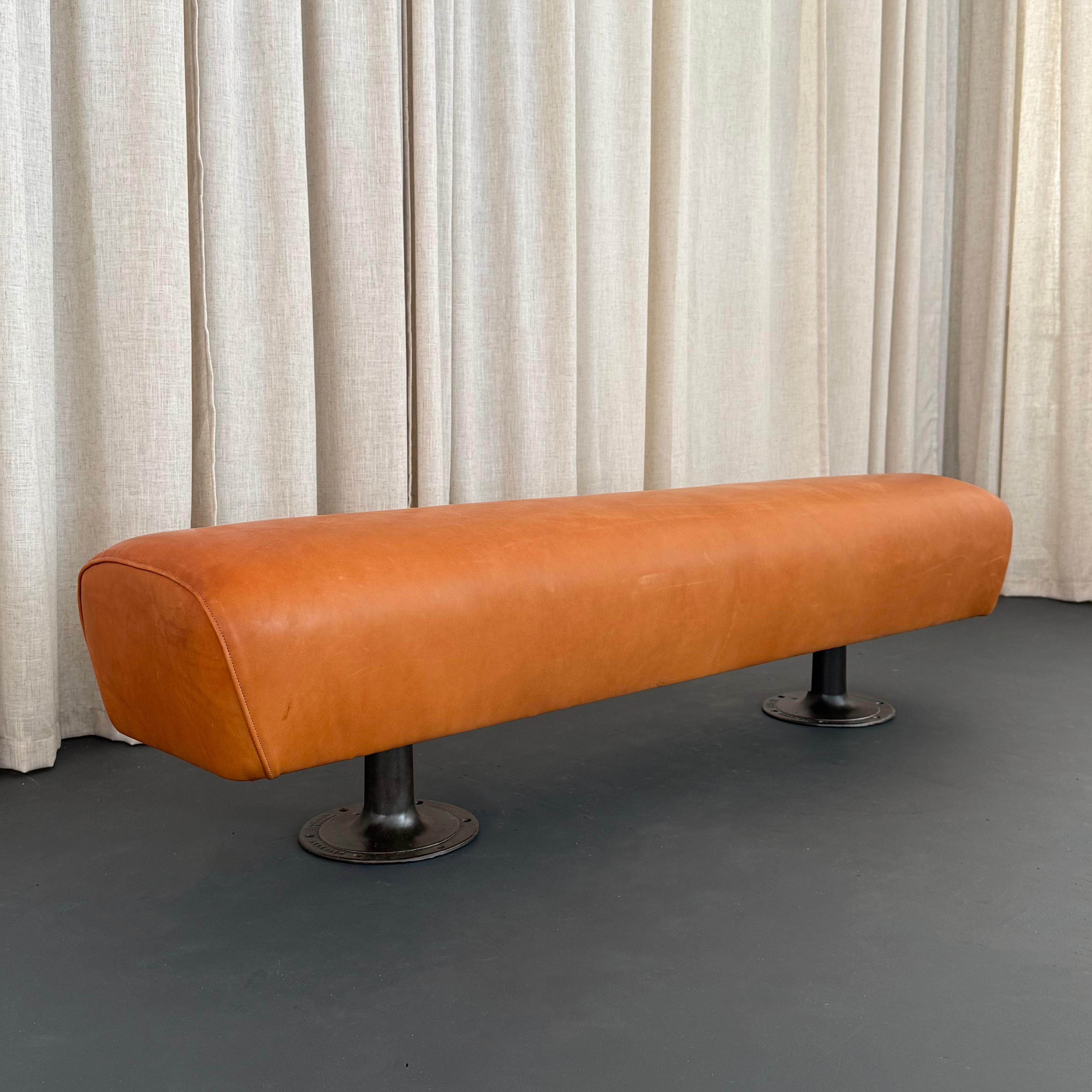 Ce banc de gymnase industriel sur mesure comprend un cheval d'arçon datant du milieu du 20e siècle, récemment recouvert de cuir souple roussâtre, associé à des pieds en fonte d'usine antiques. Ce banc unique en son genre est composé d'éléments
