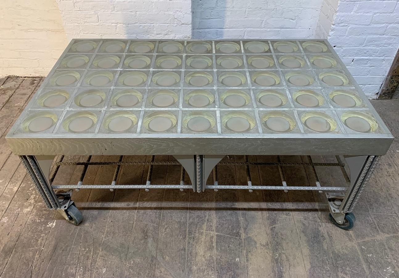 Custom, industrial steel coffee table with faceted glass top. The wheels are welded to the frame but can be removed.