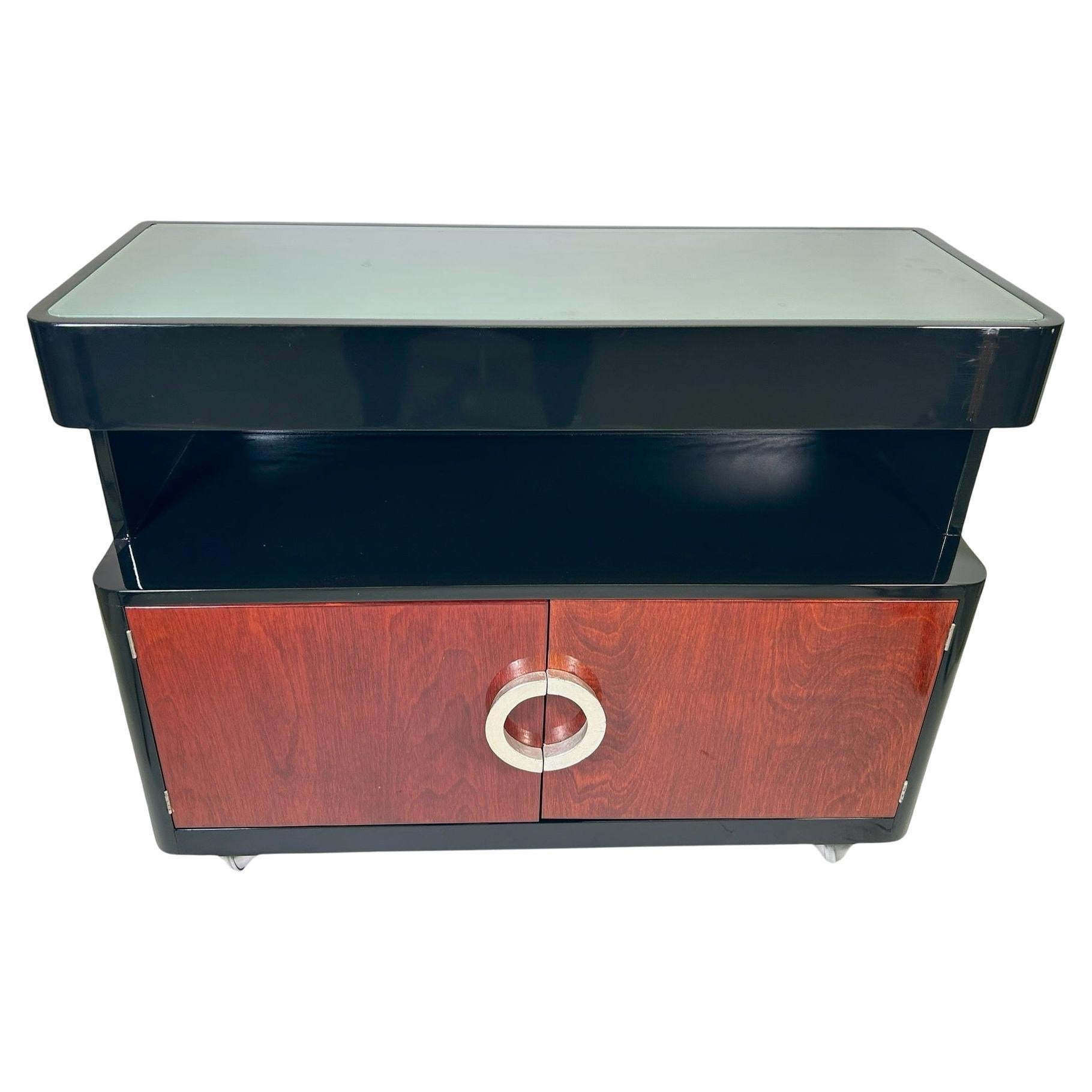 A stunning bifurcated circle-pull in silver leaf adorning 2 walnut doors for bottle storage. This Mobile bar cart glides seamlessly on the 4 silver hued chrome ball casters. The remainder of the piece is piano lacquered. An open shelf to hold