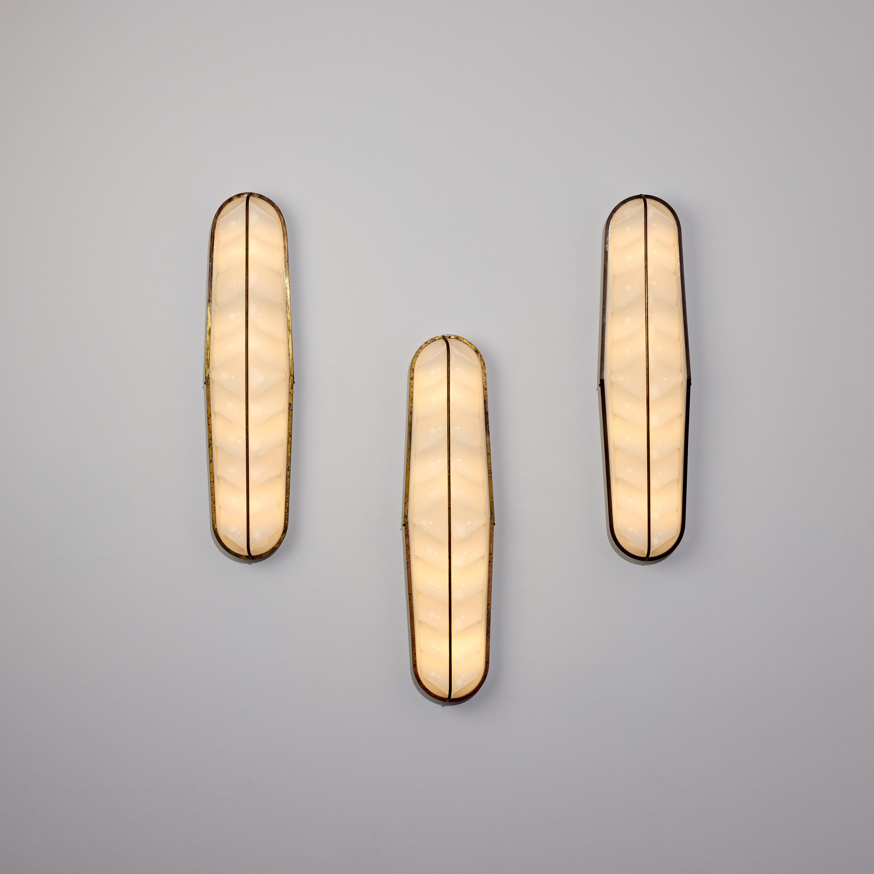 Apliques italianos a medida. Diseñado y fabricado en Italia, hacia la década de 1960. Llamativos difusores acrílicos moldeados anatómicamente con detalles de latón patinado. Estos apliques son ligeros gracias a los materiales elegidos. Cada aplique