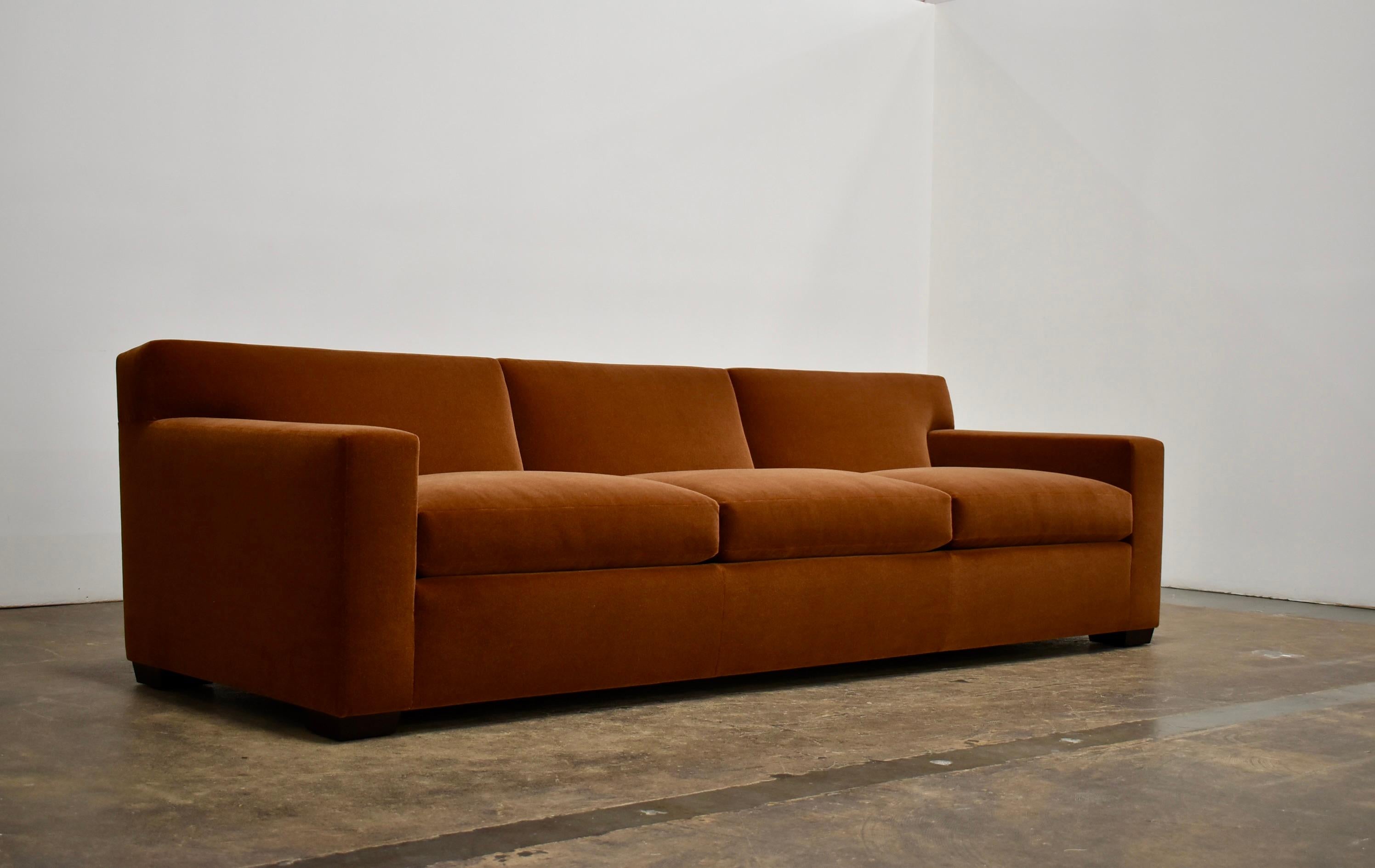 Das klassische Sofa im Stil von Jean Michel Frank, handgefertigt von Classic Design, mit einem Innenrahmen aus massivem Hartholz, klassischer handgebundener Federung, weißen Kissen aus Gänsedaunen und Federn und konisch zulaufenden Holzbeinen.