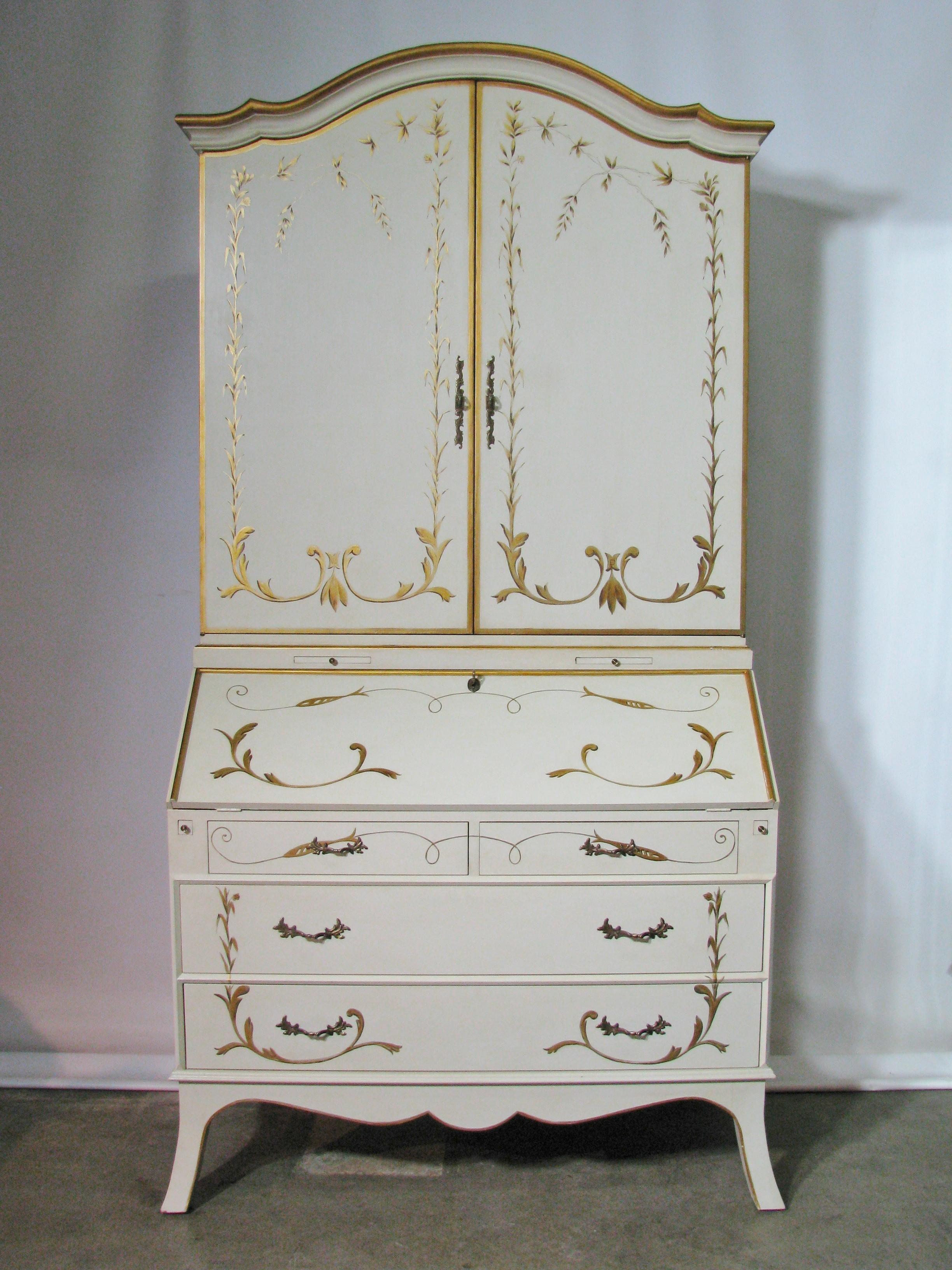 Striking slant-front secretary bookcase by Julia Gray, Ltd. Rich ivory-painted color inside and out. Accented with hand-painted gilt motifs on the front and sides, as well as on the interior sides of the doors. The slant front opens and rests on two