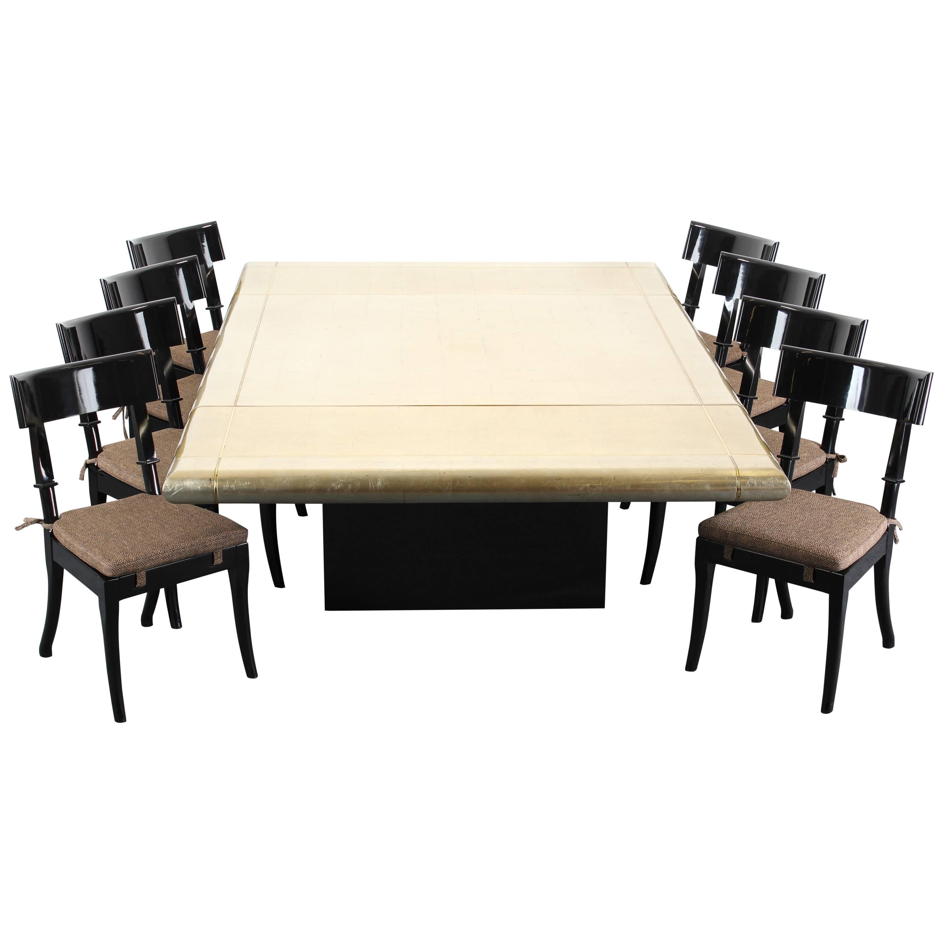 A fabulous custom-made gold leaf and black lacquered dining table on casters with two leaves which seats 10-12 people. The table and leaves have an inlaid bronze border. The top is lacquered with hand-applied gold leaf squares. Very good condition