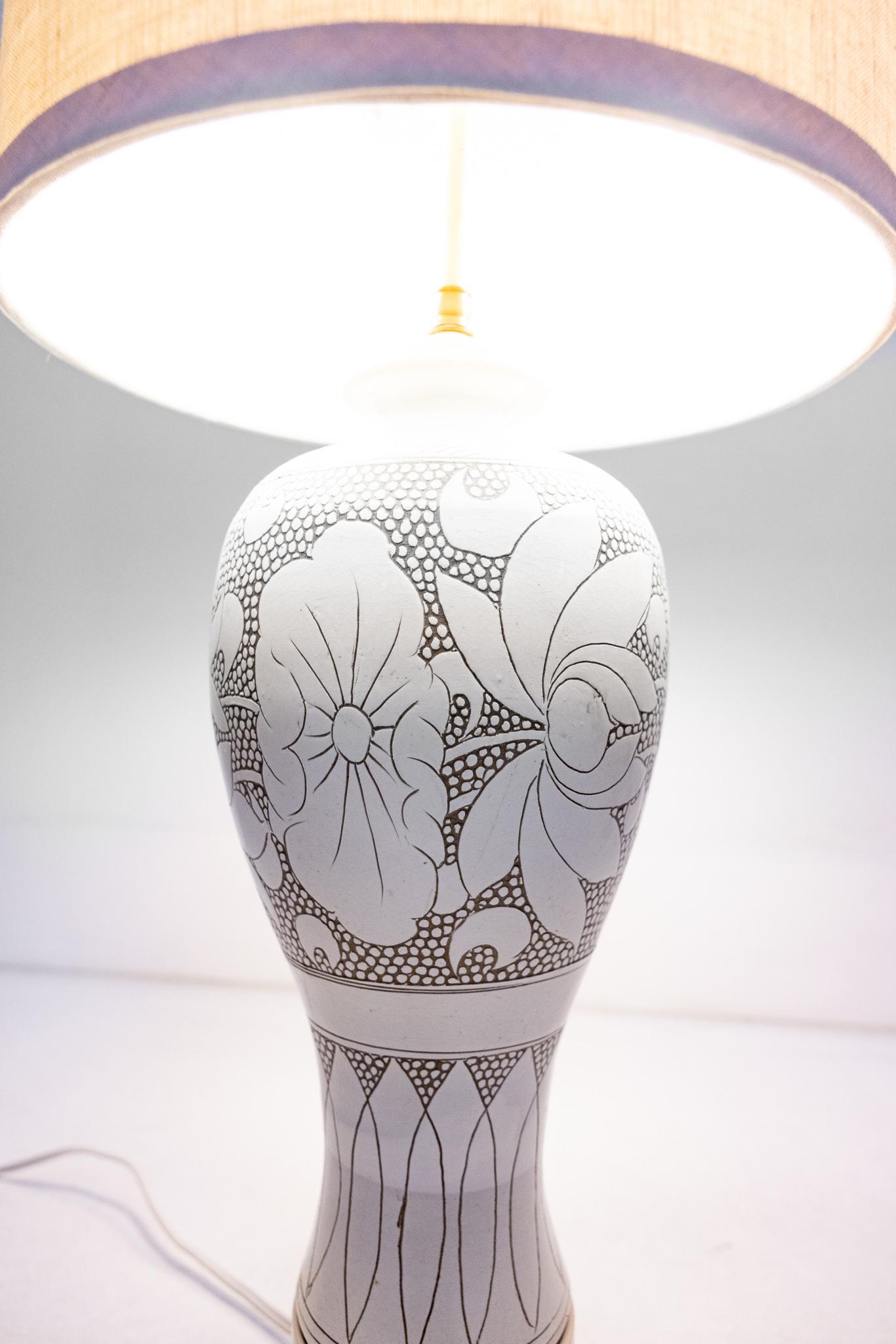 This urn lamp has an elegant floral motif and is situated on a 3 inch wooden base. Seemingly oversized it is a Haines signature treatment. It is a custom piece by Billy Haines and came from the estate of Henry Bloch of H&R Block, purchased directly