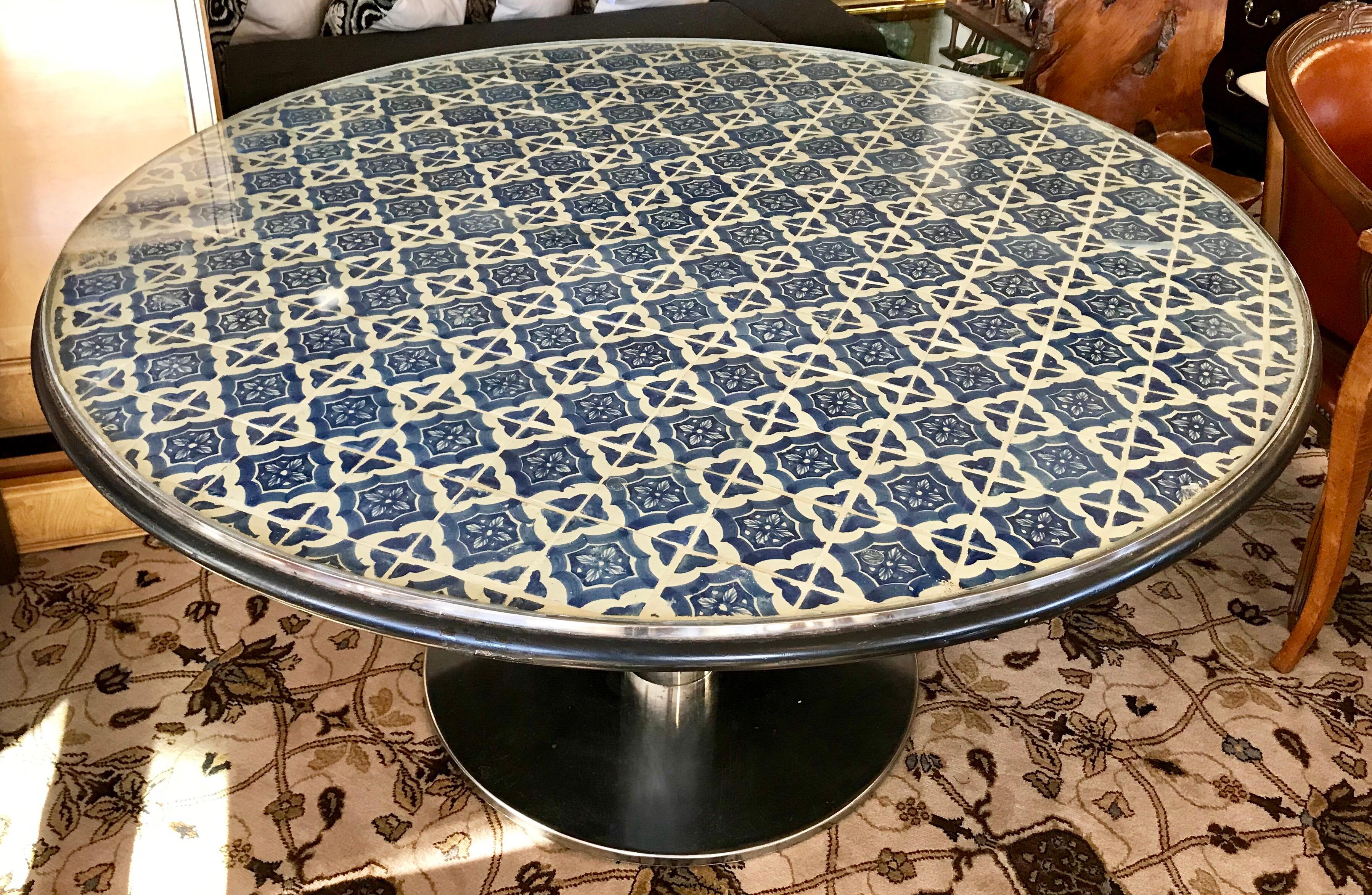 Magnificent custom round tile top table on a stainless steel pedestal base. Top is made of hand painted blue and white Spanish tiles and is protected with a glass top. Tiles are fitted inside a steel frame and the edge of table is a black painted