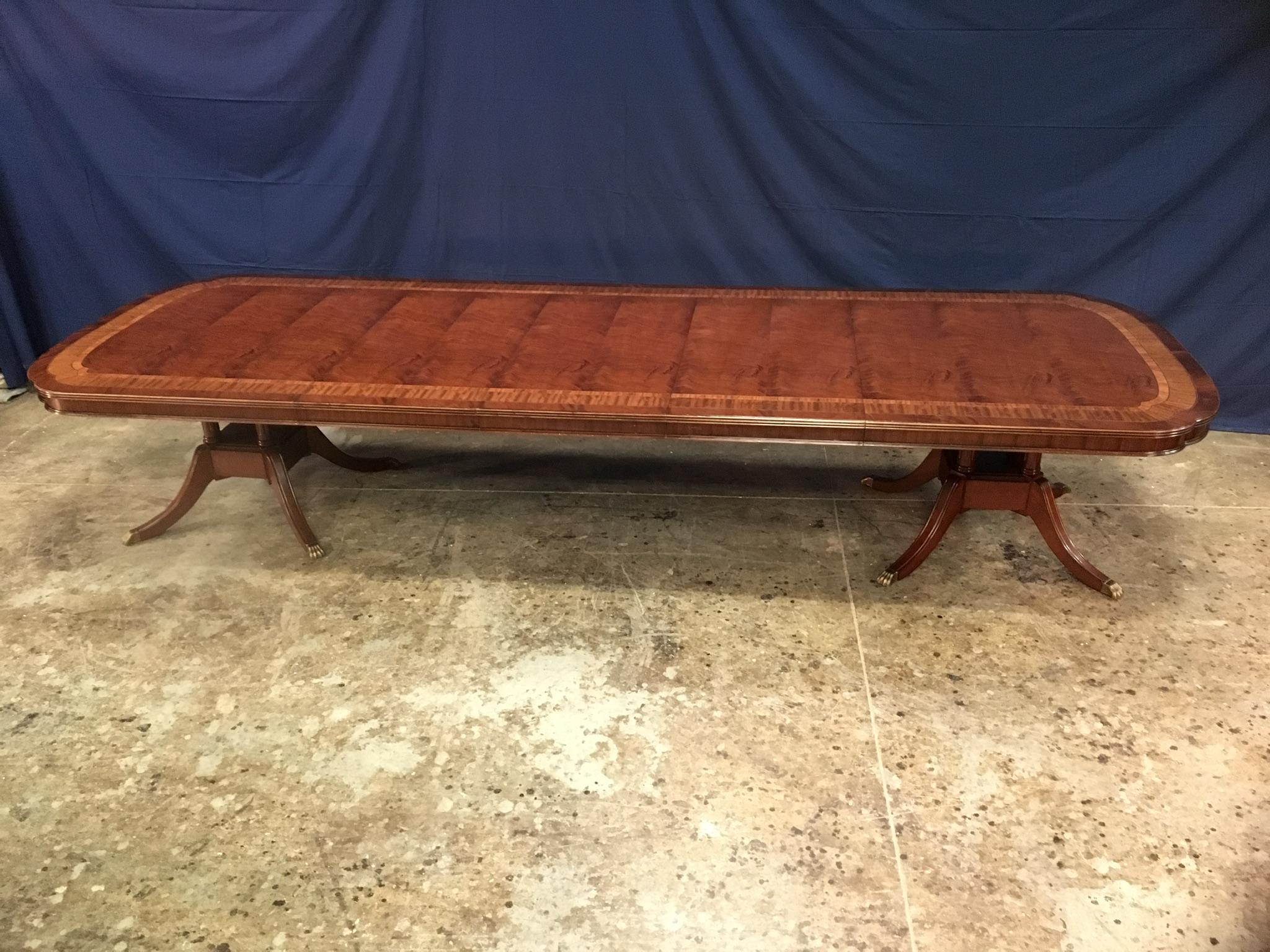 This is a made-to-order large traditional mahogany banquet/dining table made in the Leighton Hall shop. It features a classic scallop corner design with a field of slip-matched swirly crotch mahogany from west Africa and tulipwood, satinwood and
