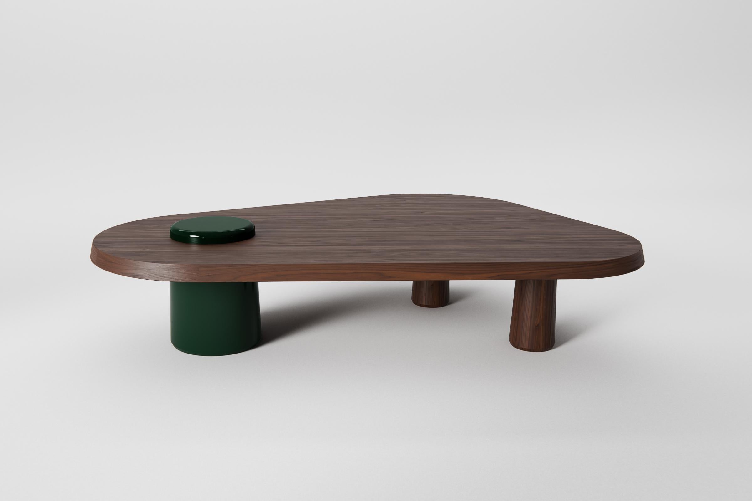 Sculptural coffee table features an organic, asymmetrical top crafted from solid walnut. The form is supported by a combination of two turned walnut legs and a bold cylindrical base finished in a deep green high-gloss lacquer. Handmade in the
