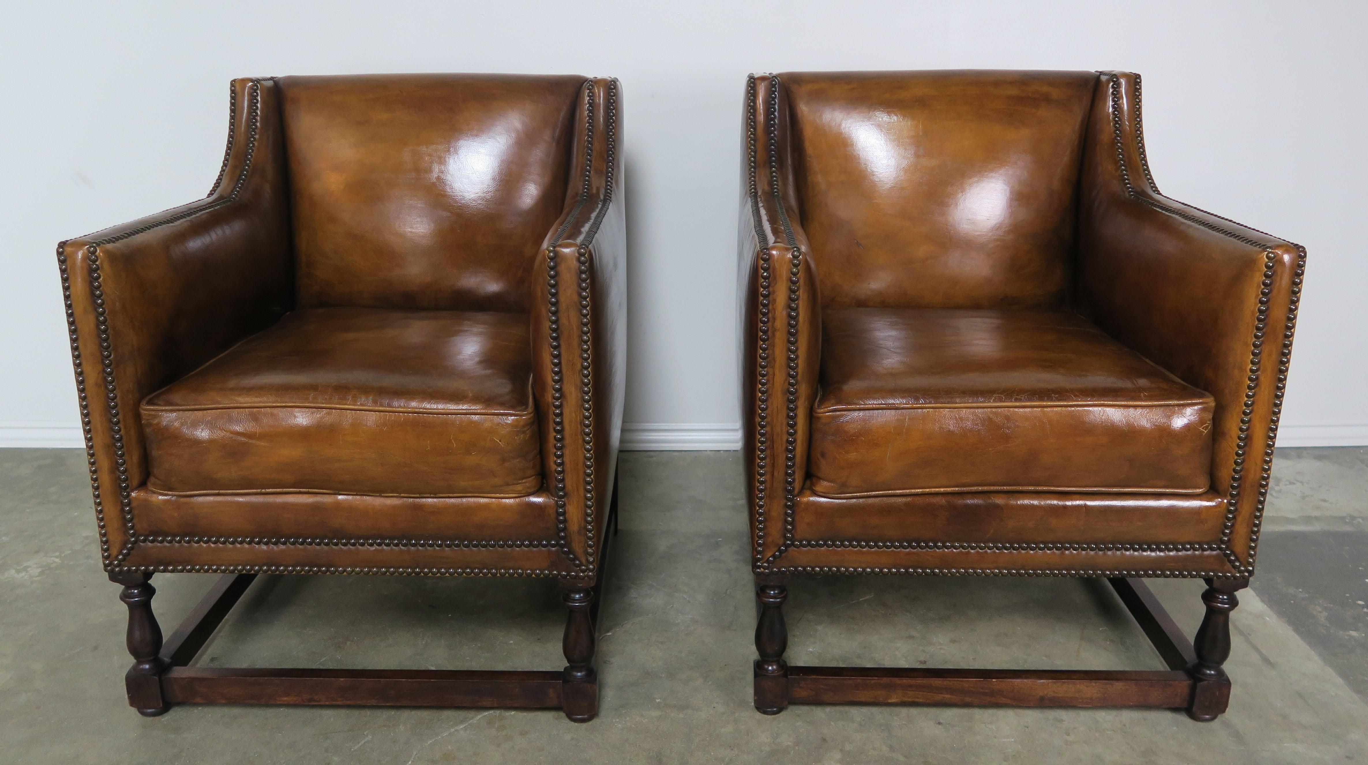 Pair of custom leather upholstered armchairs made by Melissa Levinson antiques. The walnut finished simple frame is upholstered in a beautiful worn looking distressed leather and finished with antique brass nailhead trim detail. We can make this