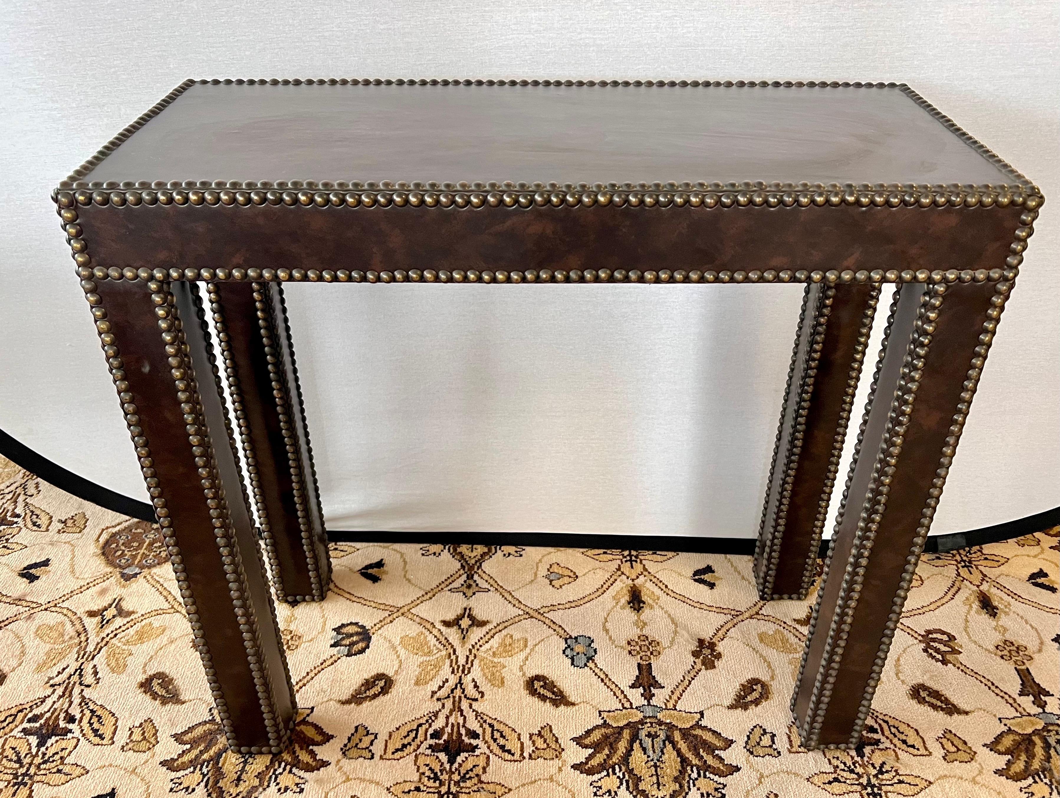 Handsome pair of custom brown leather wrapped console tables with clean lines.
Finished with antique brass nailheads.