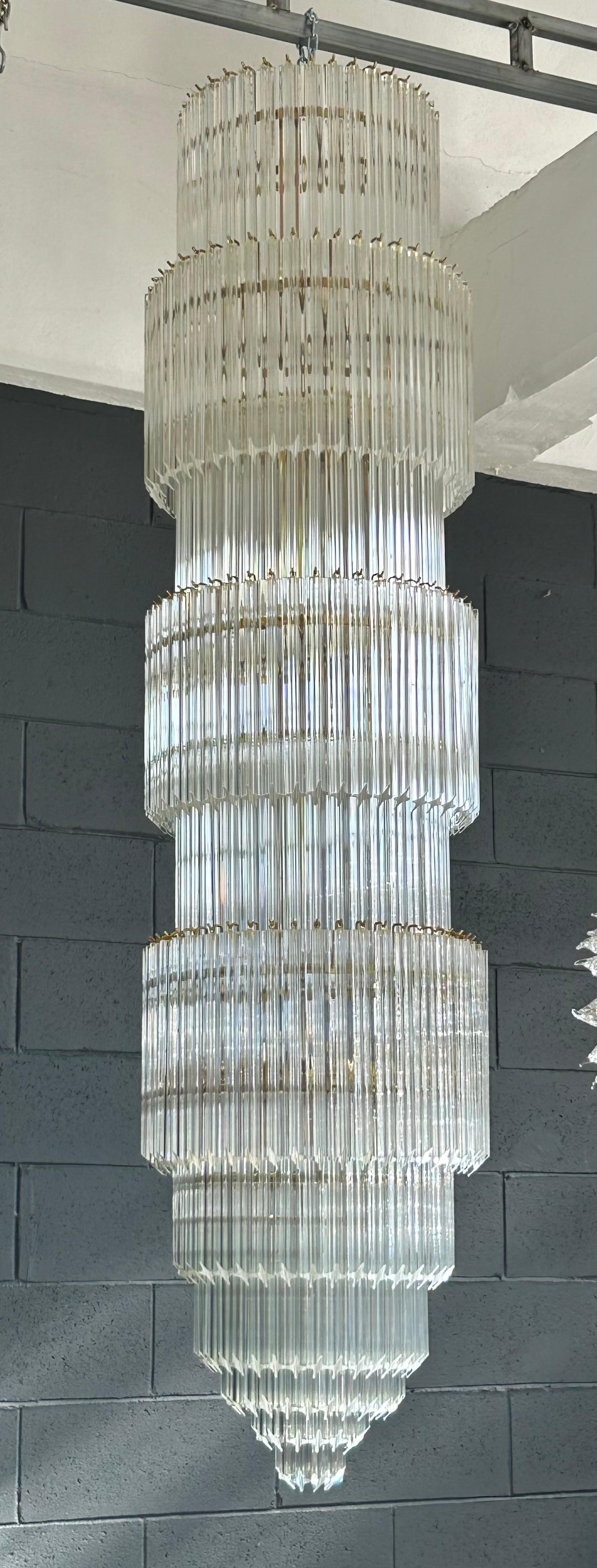 Lampadario personalizzato a più livelli con cilindri a forma di stella in vetro trasparente di Murano. Può essere realizzato in altri metalli.