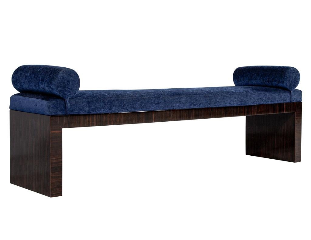 Carrocel custom Macassar Art Deco inspired bench. This bench is part of the Carrocel Custom collection. handcrafted and hand polished in Macassar wood. It is upholstered in a Classic blue velvet with attached bolsters on the ends for added detail.