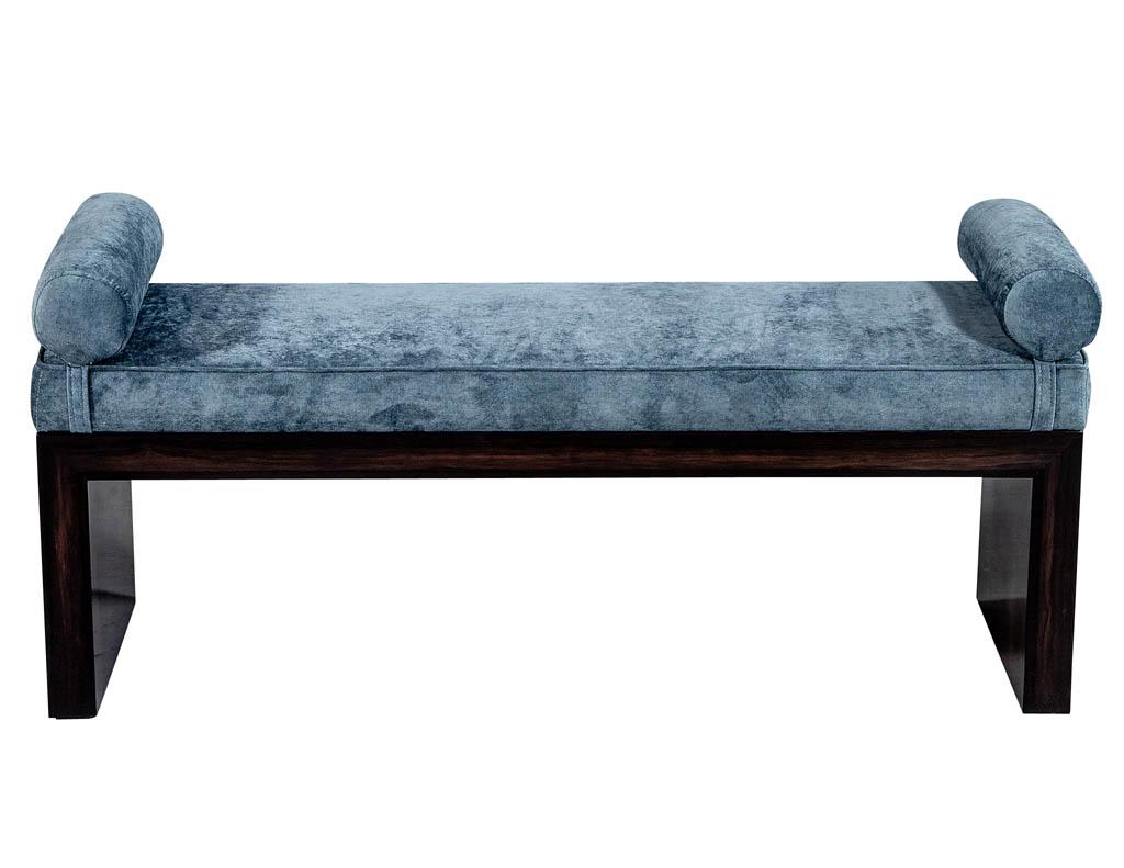 This bench is part of the Carrocel custom collection. Handcrafted and hand polished in Macassar wood. It is upholstered in a classic pale blue velvet with attached bolsters on the ends for added detail. This bench is a timeless, yet modern sleek