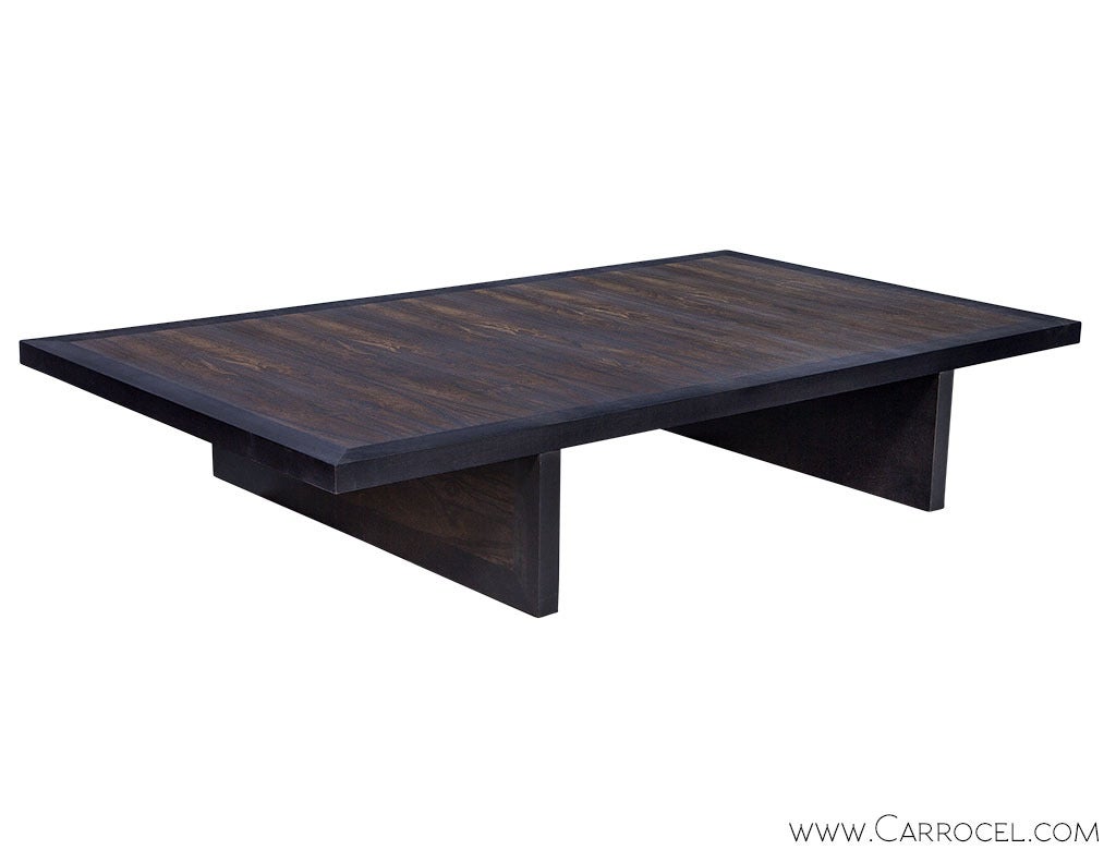 A custom made low height coffee table versatile enough to complement any typology of living room space setting. Bearing a contemporary design in Macassar ebony, with deliberately oversized proportions, the bevel edged table top projects over two