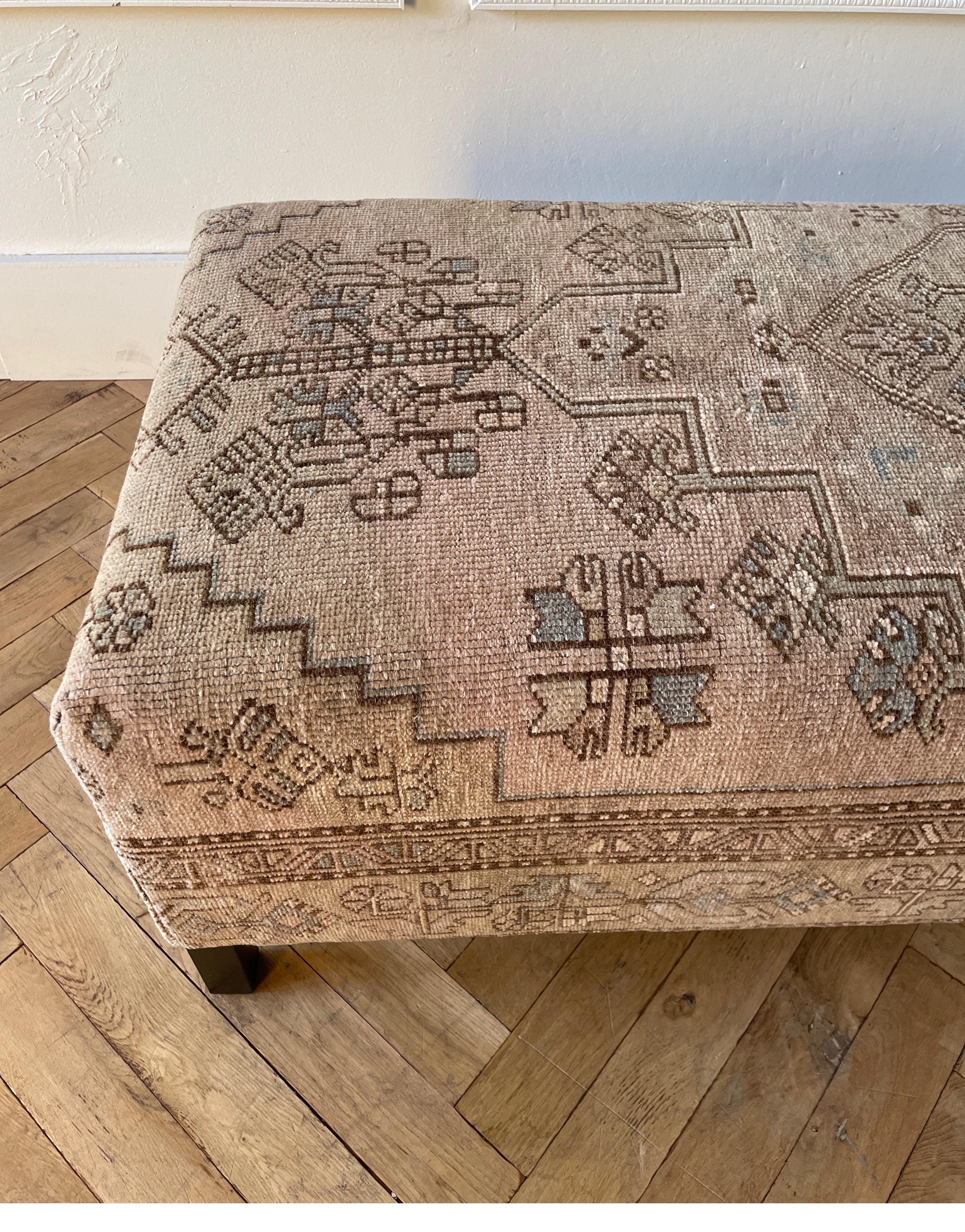 Custom made iron cocktail ottoman with vintage wool Turkish rug. Frame is metal in an antique bronze finish. Upholstered top in an antique wool turkish rug, in faded neutral tones of taupes, creams, blues, and brown and gray, salmon pink (very
