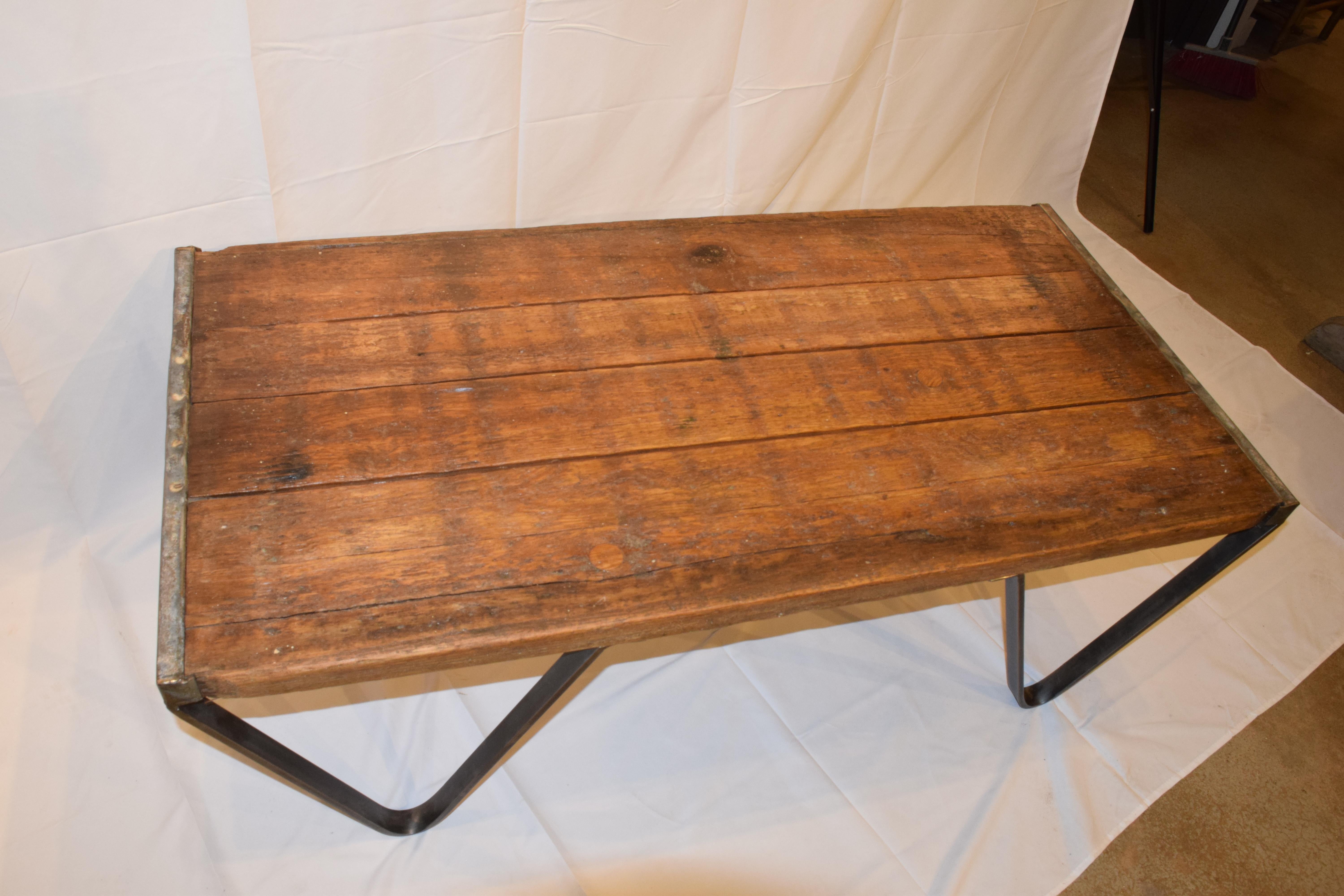 This is a coffee table newly made from an antique French brick layers pallet with a custom iron base. The wood pallet has a lovely aged and waxed patina and original metal ends. A wonderful coffee table which can be used in a traditional or modern