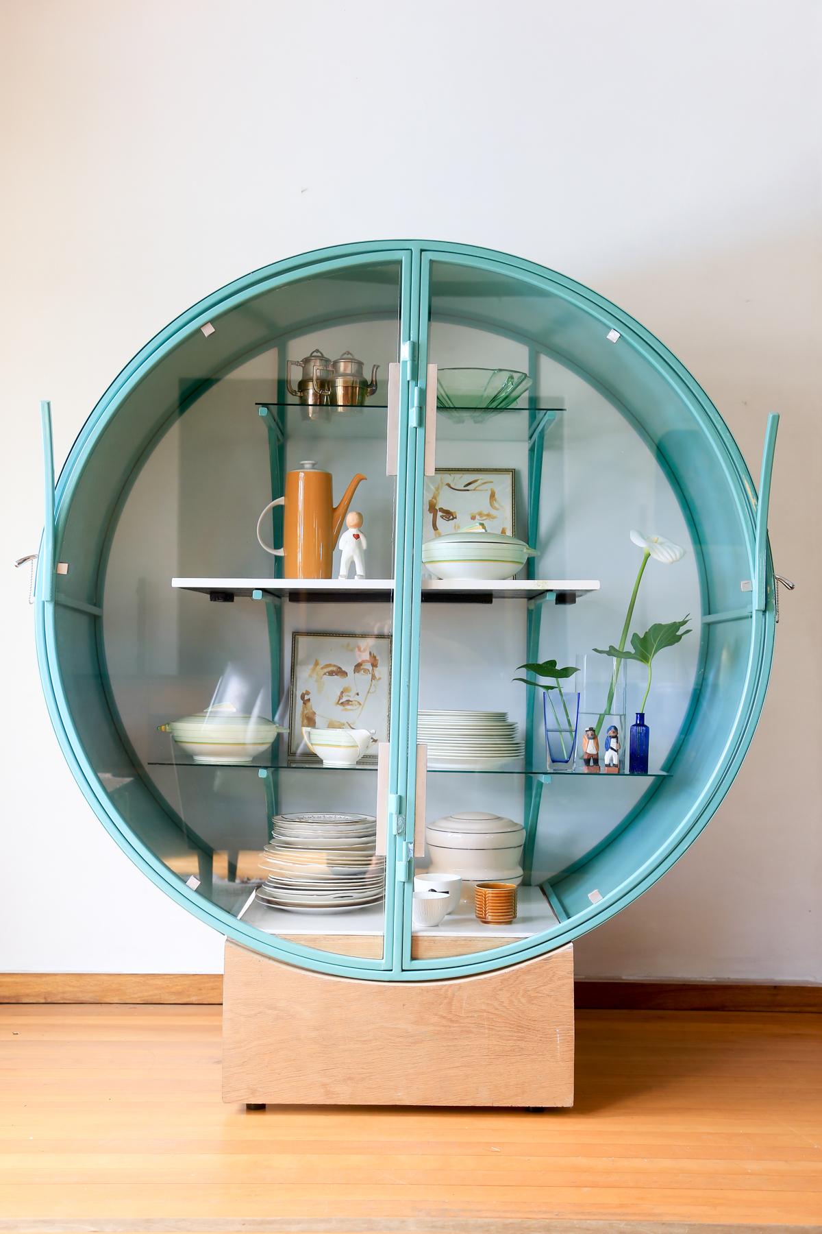This is the Audacious South African Showcase, a round display cabinet designed and hand made by Glen Napier. It is a bold contemporary take on art deco. It is made of steel, safety glass, and a raised wooden base that creates a floating effect. It