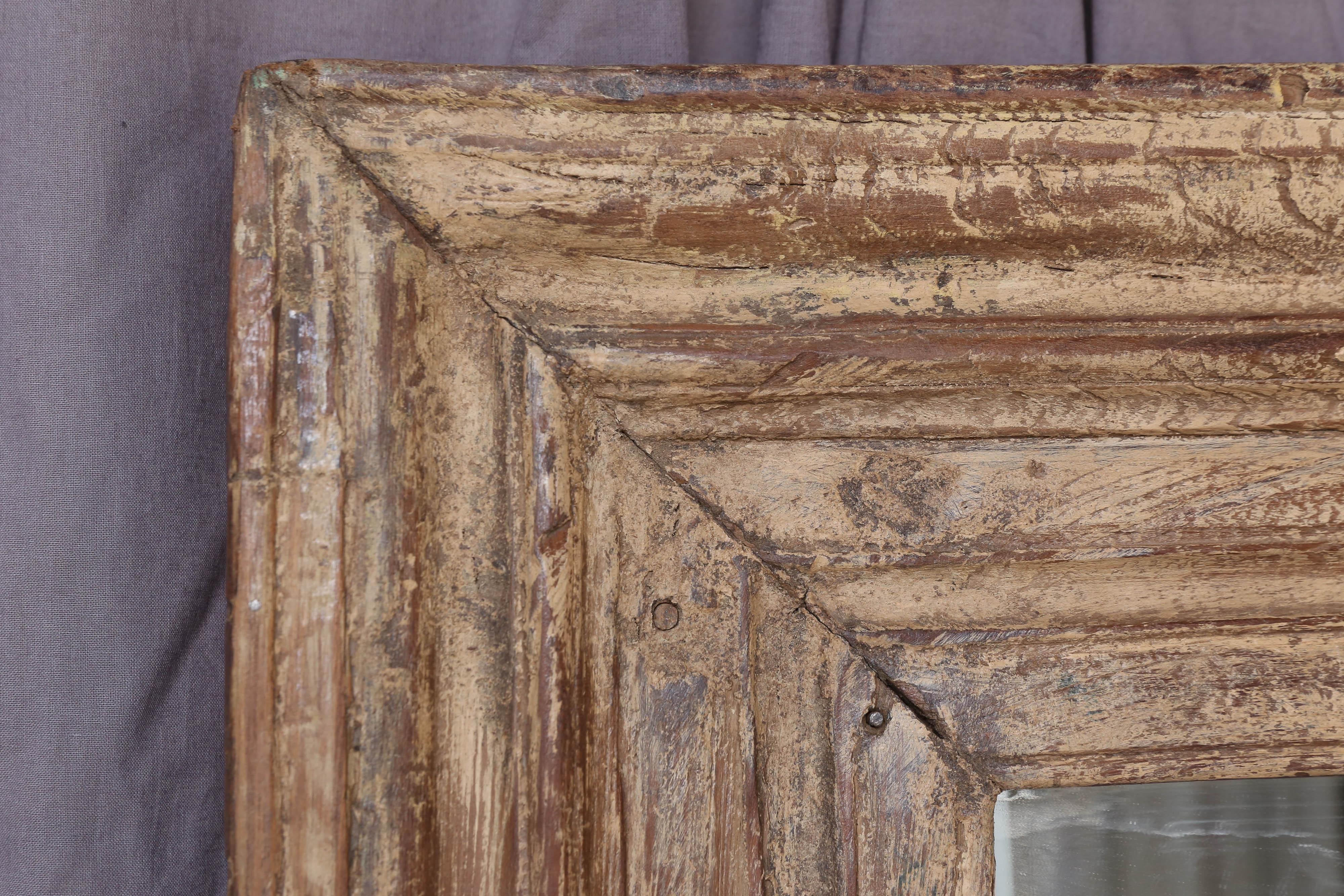 The frame for the mirror comes from a window frame of an 19th century plantation home.
The frame was made in solid teak wood and is heavy. It was originally painted and repainted several times. Some original paints can be seen still sticking to the