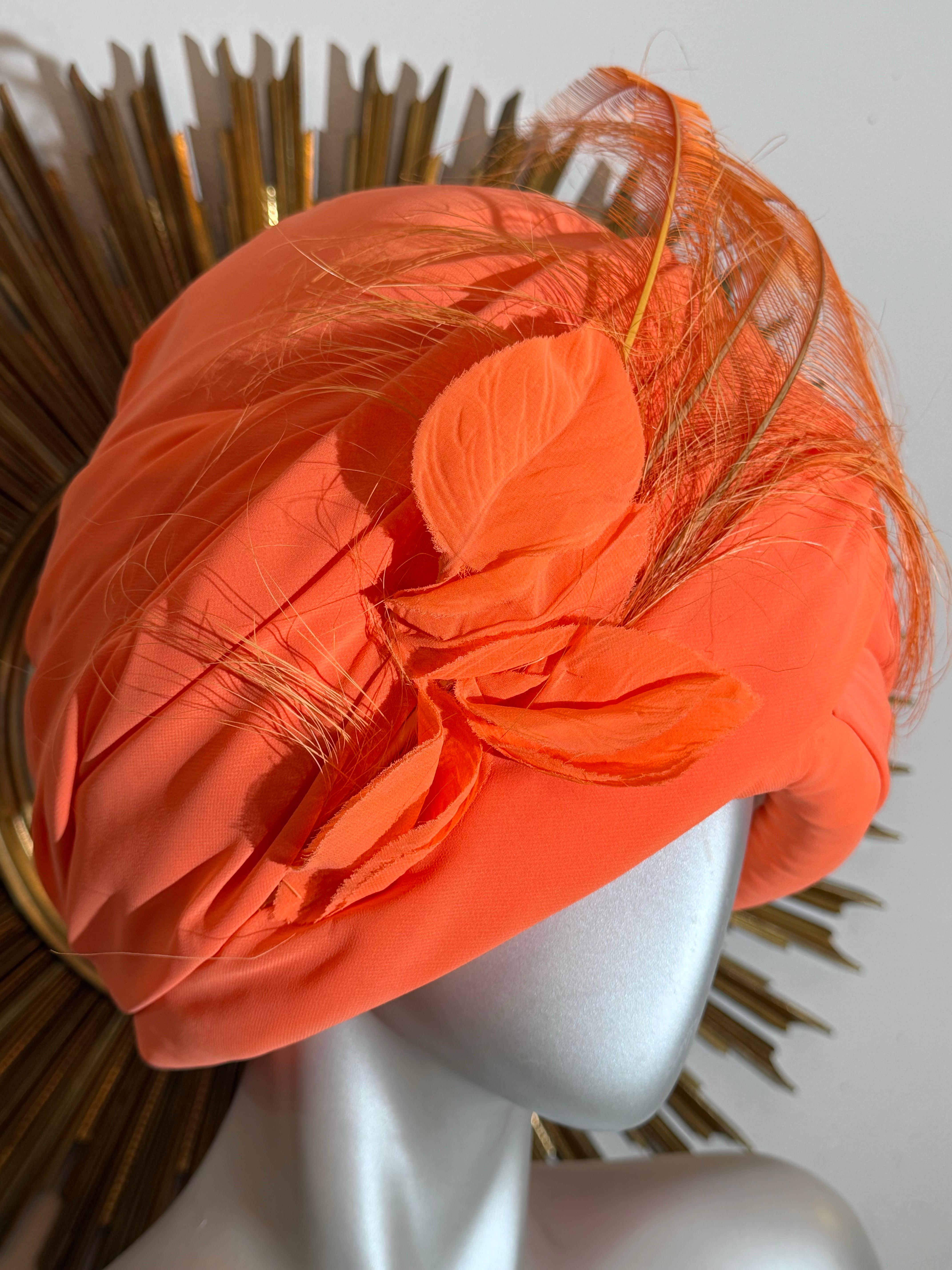 Turban en mousseline de soie orange drapée avec plume d'autruche chantée sur le devant : un style à fort impact dans une couleur qui fait tourner les têtes !  Joliment structuré et paddé en crêpe de soie avec soie.  doublure en satin. Peignes