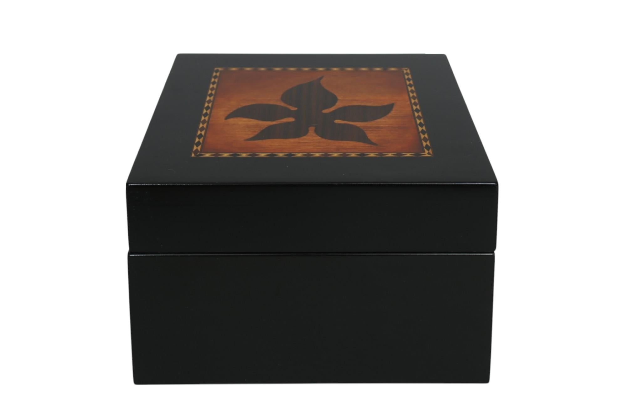 A beautiful handmade jewelry box in ebony, by Lion Crest Woodworking of Sarasota, FL. The jewelry box top is decorated with a square of maple framed with an inlaid band of fine strips, and triangles of sapele wood to create a diamond pattern. In the