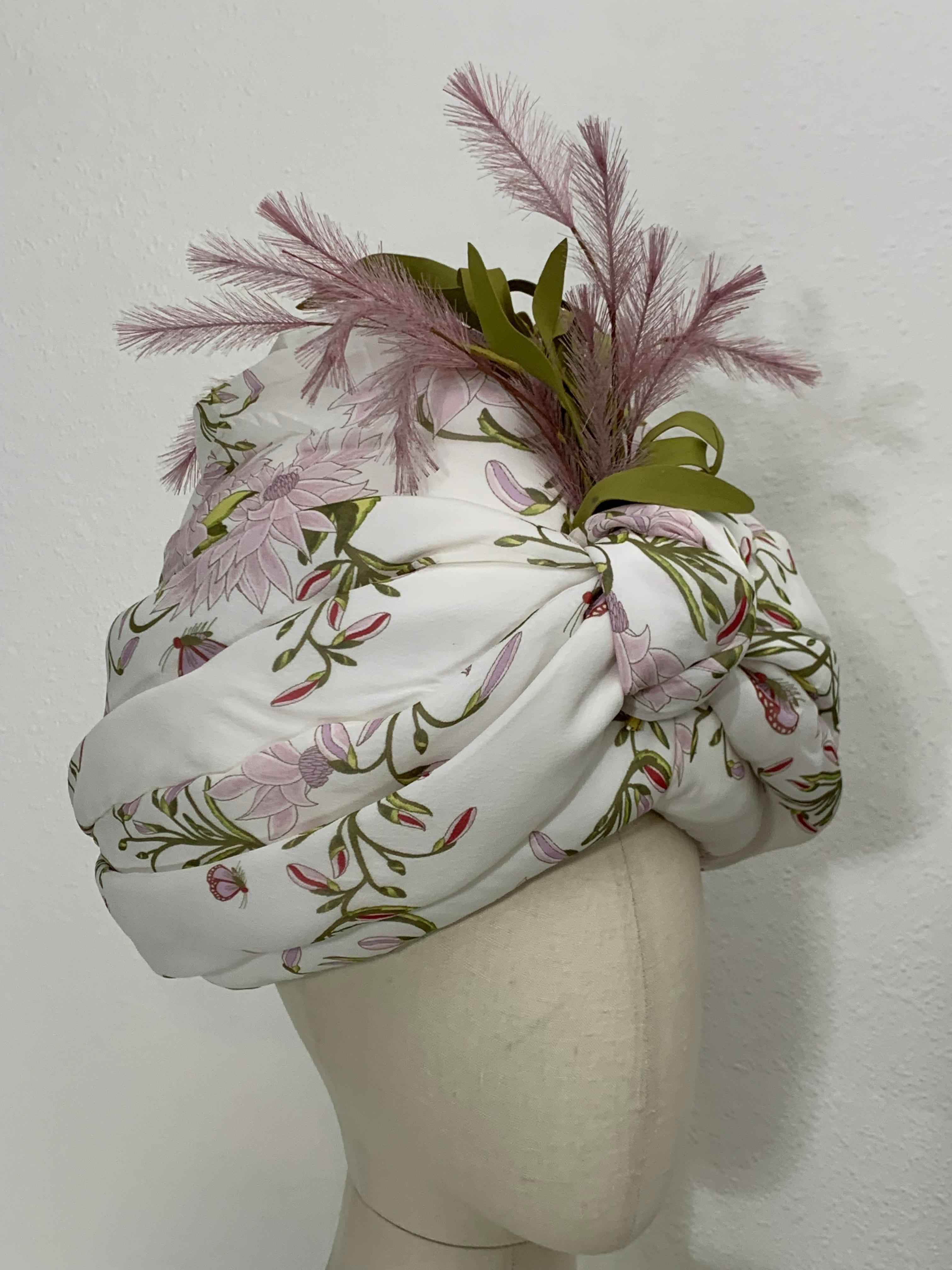 Turbante in chiffon di seta con stampa a giglio, fiori di piume e foglie verdi sul davanti: Creato da Suzanne Couture Millinery. Motivo floreale rosa e verde su fondo bianco in una forma audace, avvolto, drappeggiato e annodato sul davanti su una