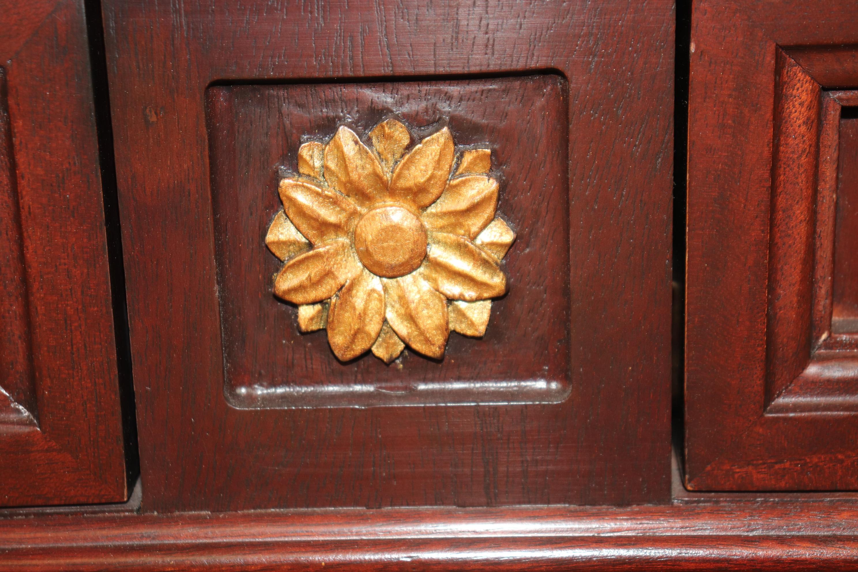 Voici un magnifique buffet en acajou et doré de style Directoire français. Le buffet présente des éléments floraux sculptés et des ferrures en bronze.  Il s'agit d'une pièce personnalisée avec des patins en métal pour un roulement en douceur et un