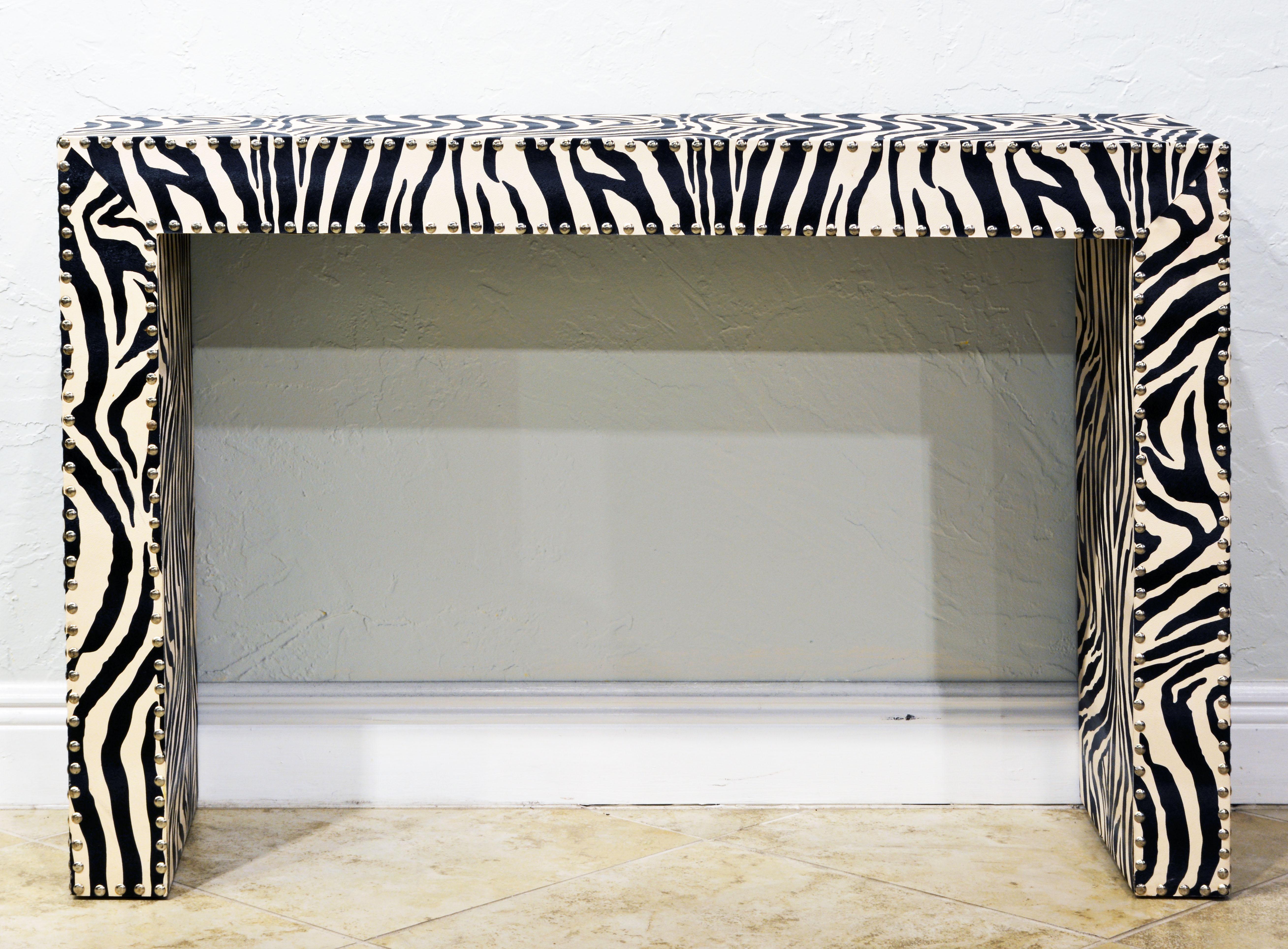 The design and proportions of this vintage Mid-Century Modern console table are strictly modern and Minimalist. It is covered in a spill proof faux zebra print on all sides including the underside and trimmed with shiny chrome nailheads along edges.