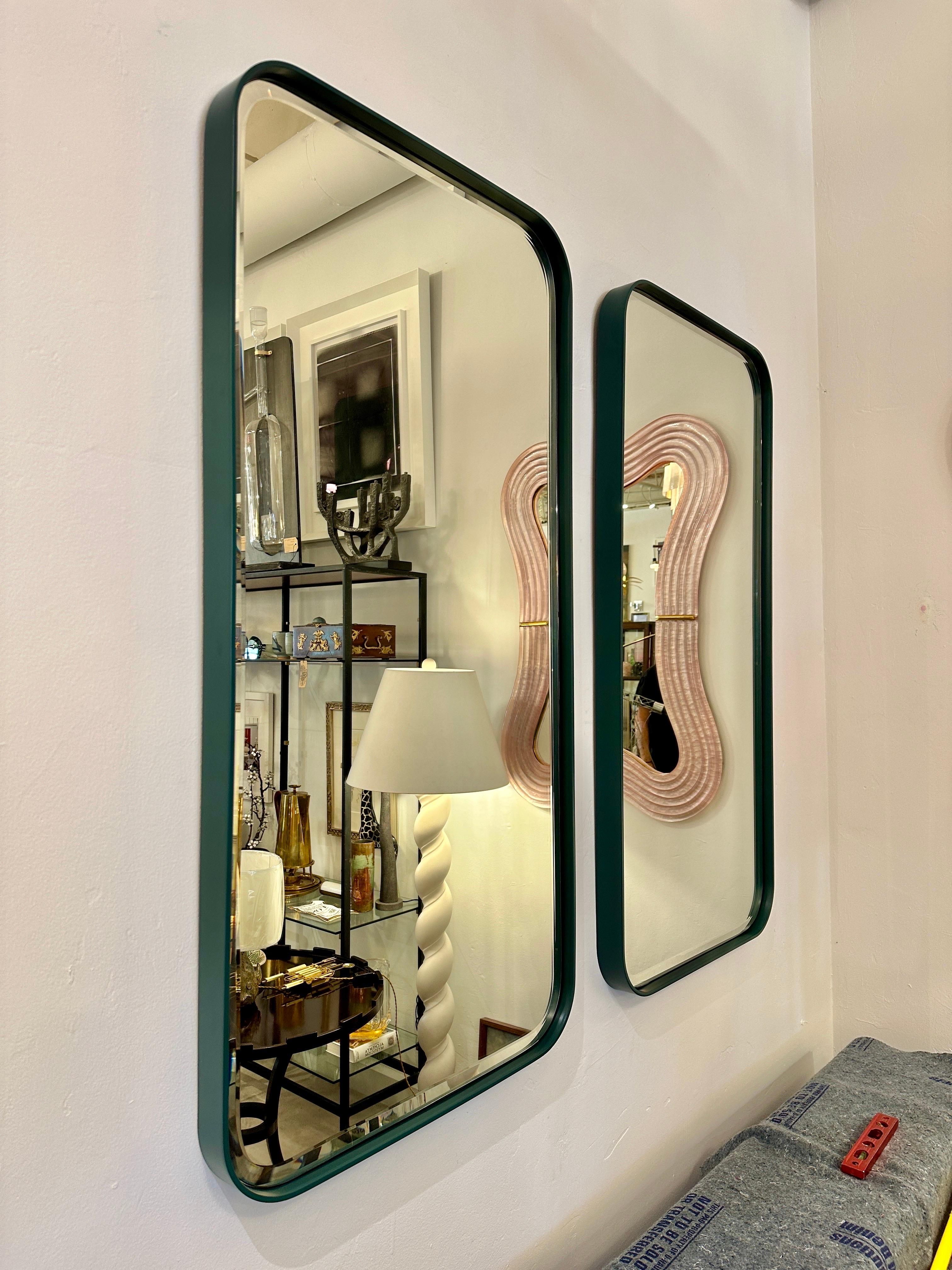 Il y a DEUX (2) disponibles de ces lourds et amusants miroirs en métal vert foncé au design moderne et au miroir biseauté.  ONE Mirror se trouve dans notre salle d'exposition d'East Hamptons, NY.