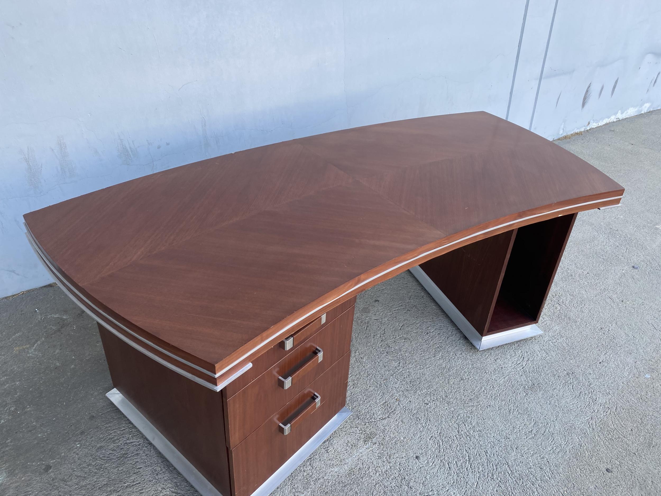 Custom made one of a kind executive desk made in the modern style sometime in the mid-1990s with a slight Art Deco flair. The desk features 3 drawers to the left and a place for a computer tower on the right. The desk has a heavy aluminum trim and