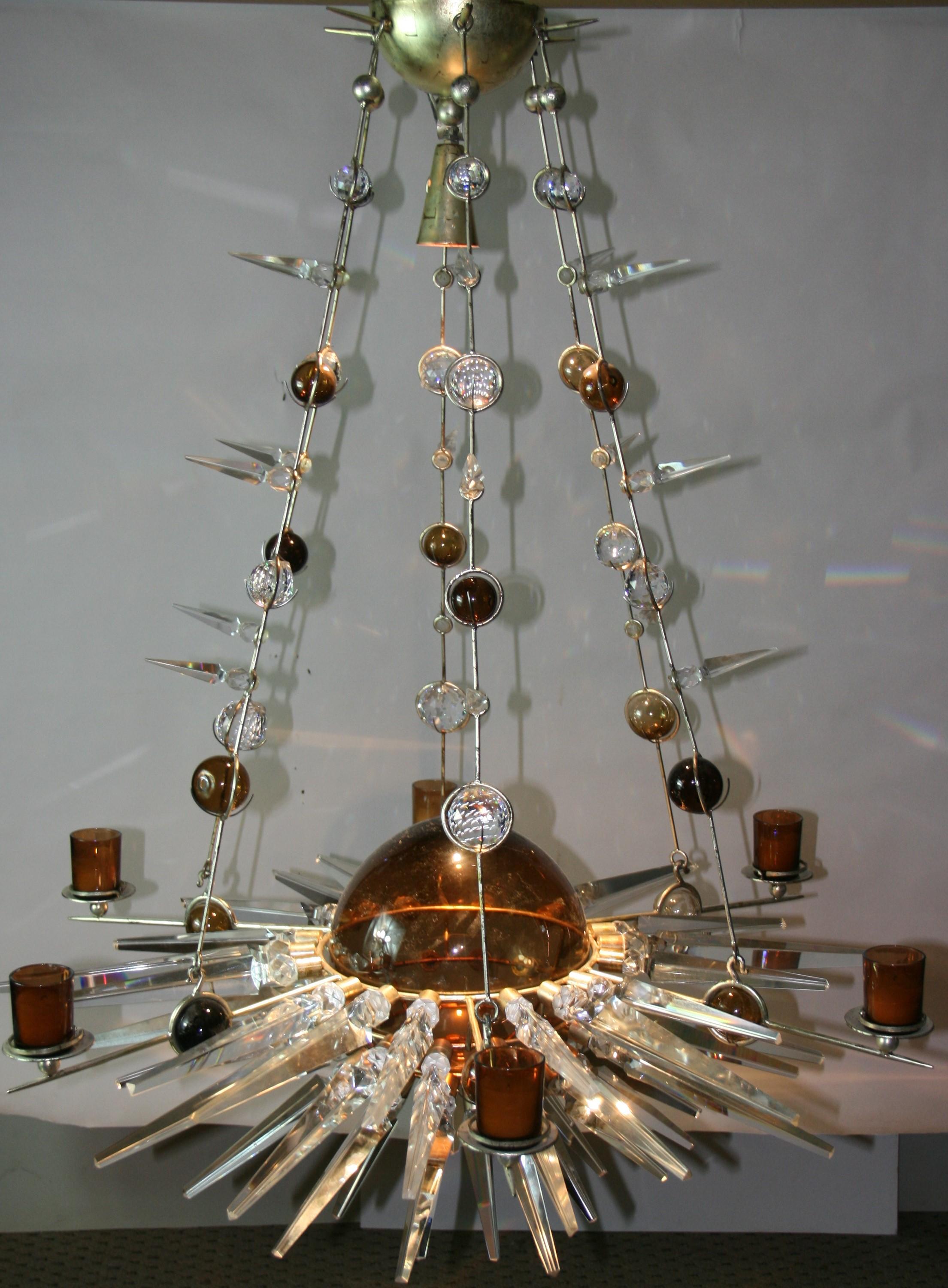 1671 One of a kind custom made Planetary chandelier.
Suspended from six silvered brass rods decorated with crystal sperars and clear and amber crystal balls.
Crystal spears surrounding a large hand blown amber class ball.
One halogen lamp shinning