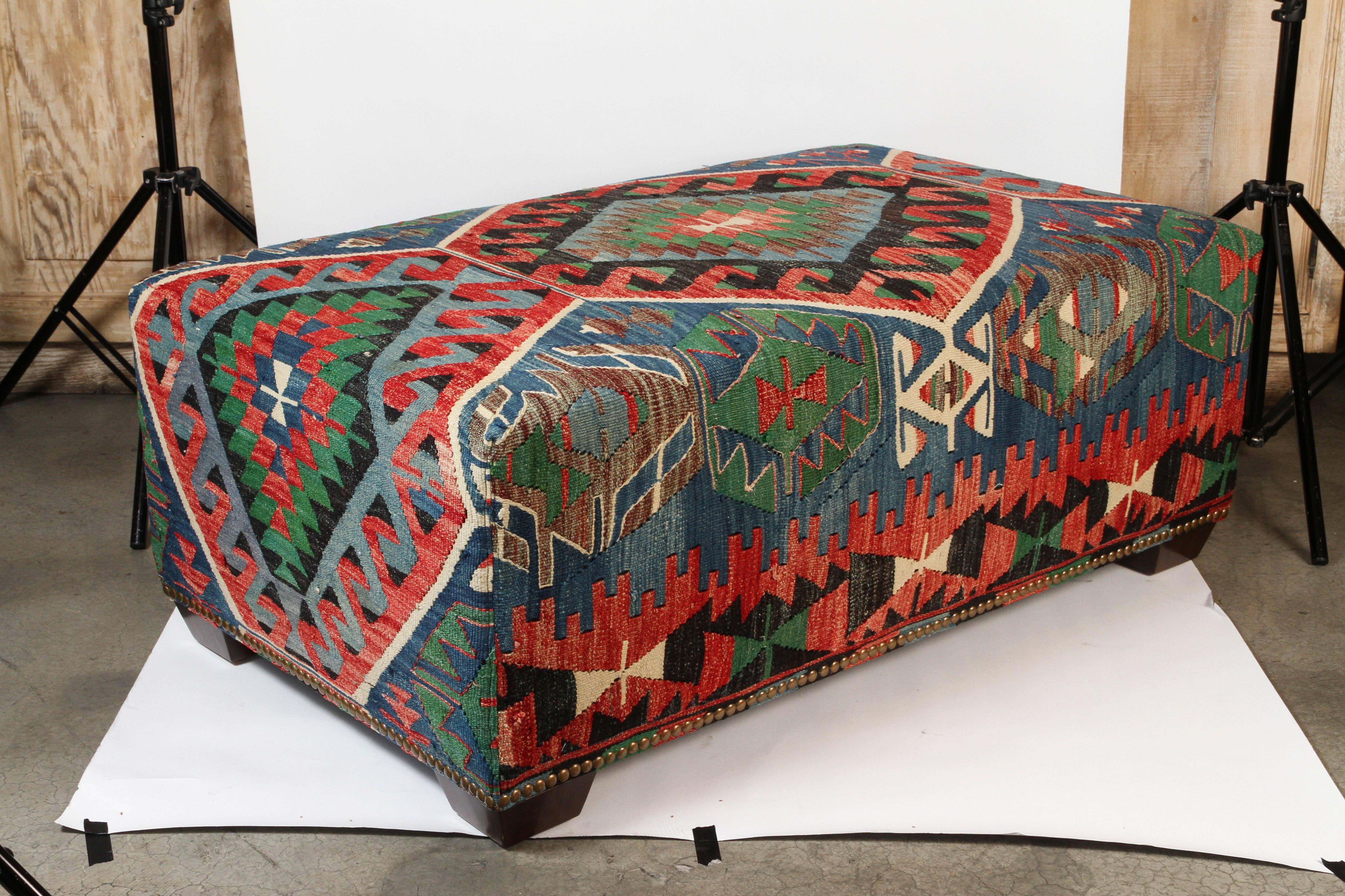 Custom-made ottoman bench using a vintage wool kilim rug with nailhead trim and wood feet.