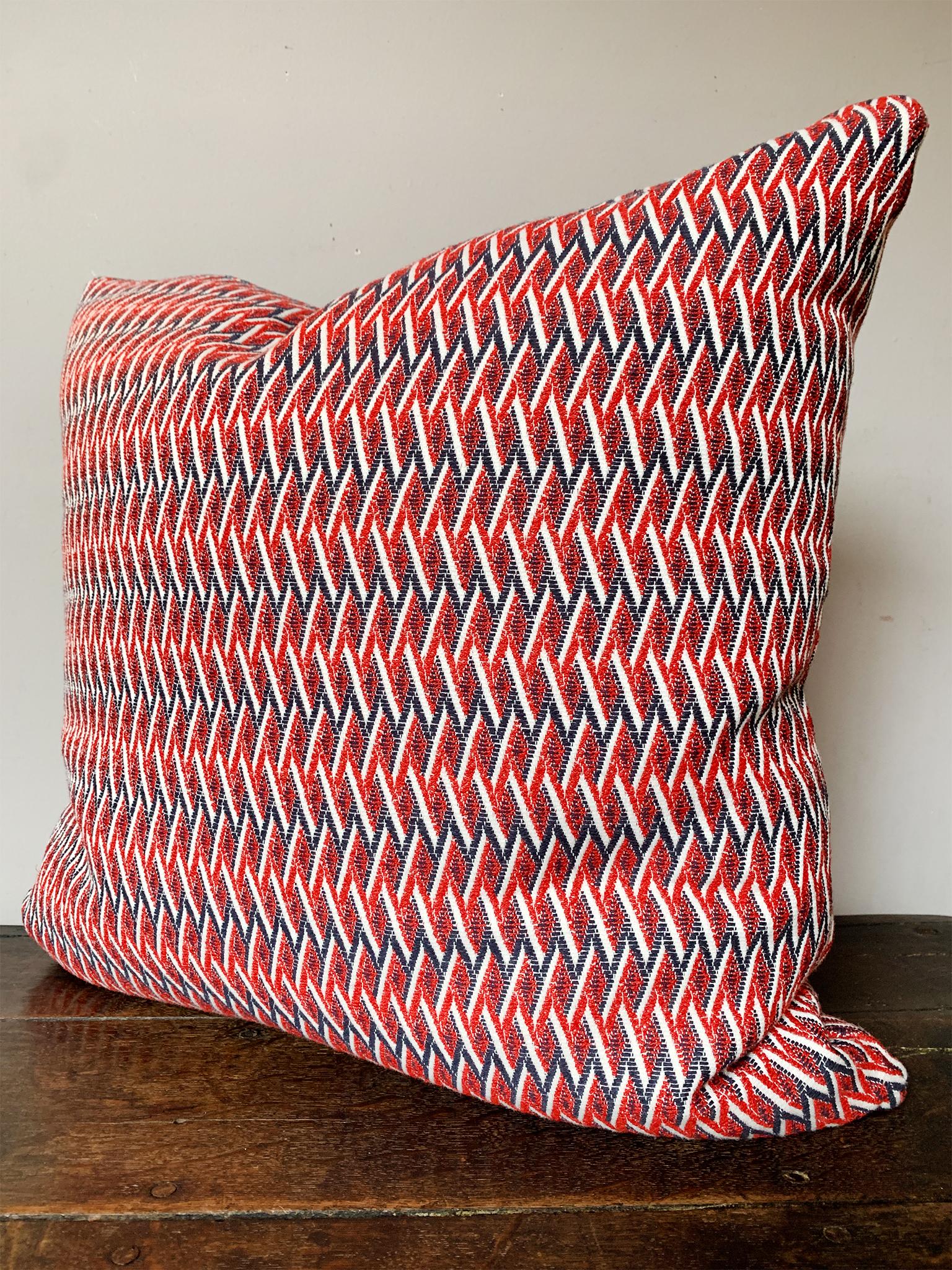 This square pillow was custom-made exclusively for Cafiero Select. It consists of a patterned weave fabric from Métaphores. This fabric has a trellis-like pattern in a dazzling palette of red, blue, and white. The cushion is a comfortable mix of