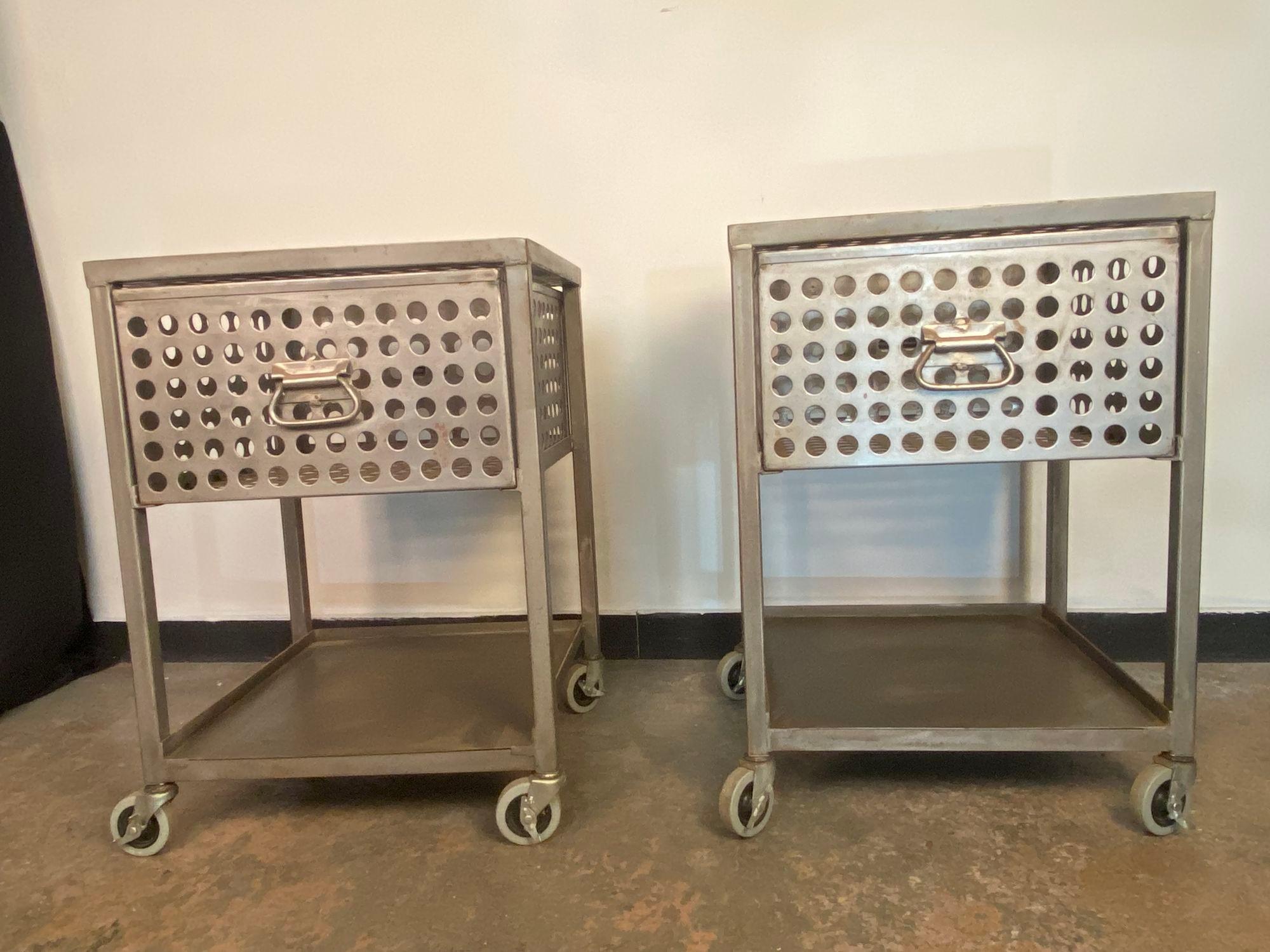 une superbe paire de tables de nuit en acier plié et perforé fabriquées sur mesure. Chacune d'entre elles comporte un seul tiroir au-dessus d'une seule étagère. Ils sont montés sur des roulettes en caoutchouc verrouillables. Une parfaite touche de