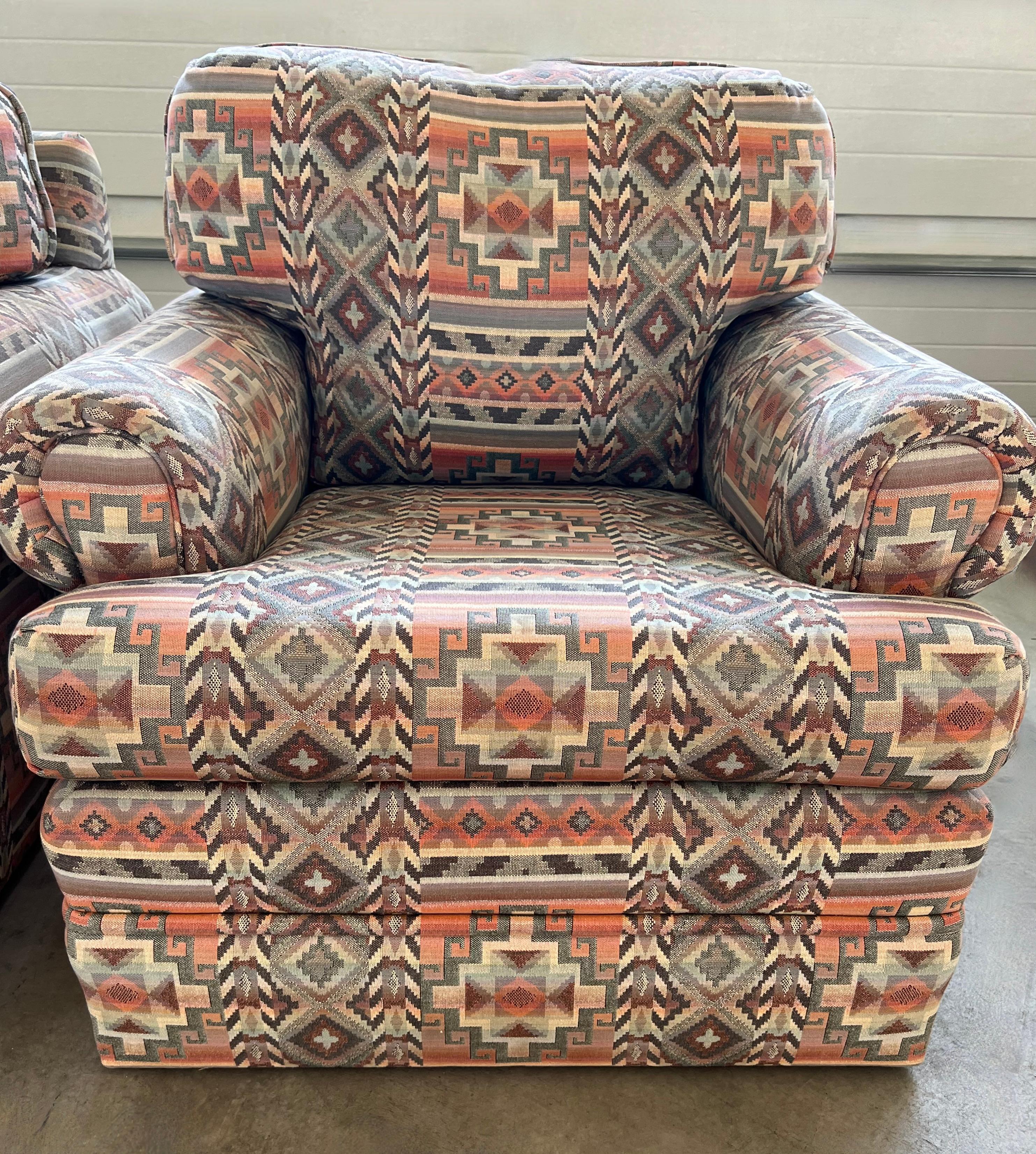 Reminiscent of Ralph Lauren's iconic southwest fabric, these two custom armchairs boast a sophisticated upholstery-grade Aztec fabric design.  The chairs have a comfy large frame with thick, well-preserved cushions and rolling armrests. The chairs