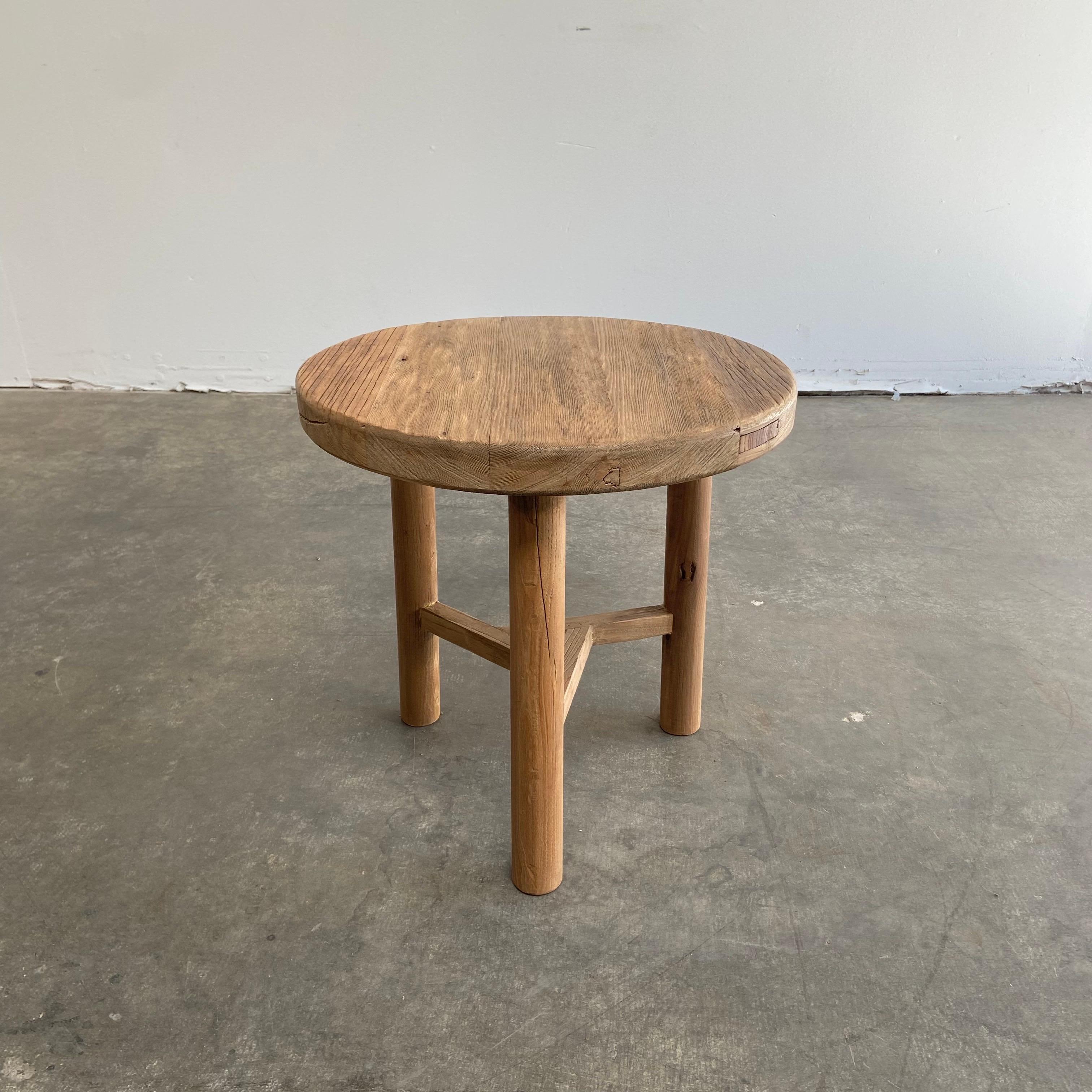 Round natural side table made from reclaimed elmwood Raw natural finish, a warm honey with gray tones in the wood. Solid and sturdy, a great side table for next to a bed, sofa, chairs. 
 Size: 24” RD x 20” H.
