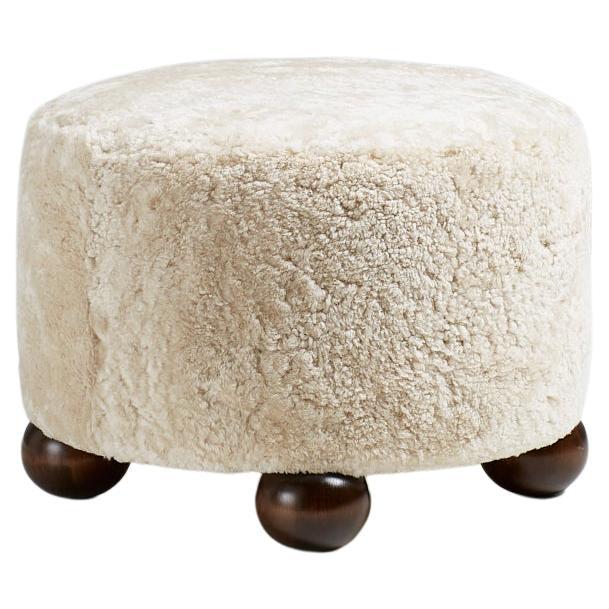 Pouf rond en peau de mouton fait sur mesure avec pieds en boule foncée