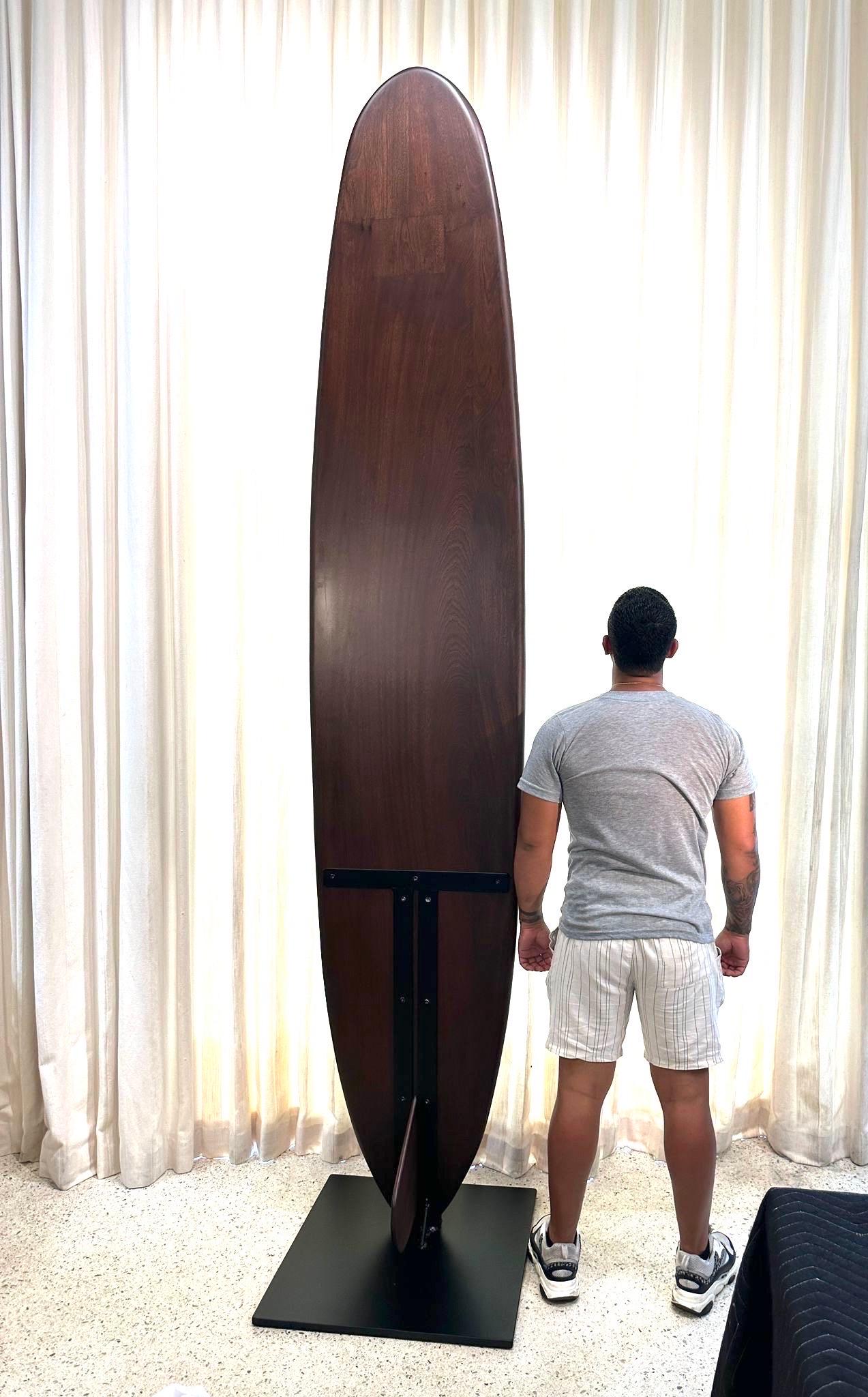 This oversized and exquisite Sapele Wood (aka African Mahogany) surfboard sculpture on a heavy iron display base was made for a Hamptons surf shop.  Beautifully refinished to its original grandeur.  This is a heavy piece.

Surfboard Base 24 inches x
